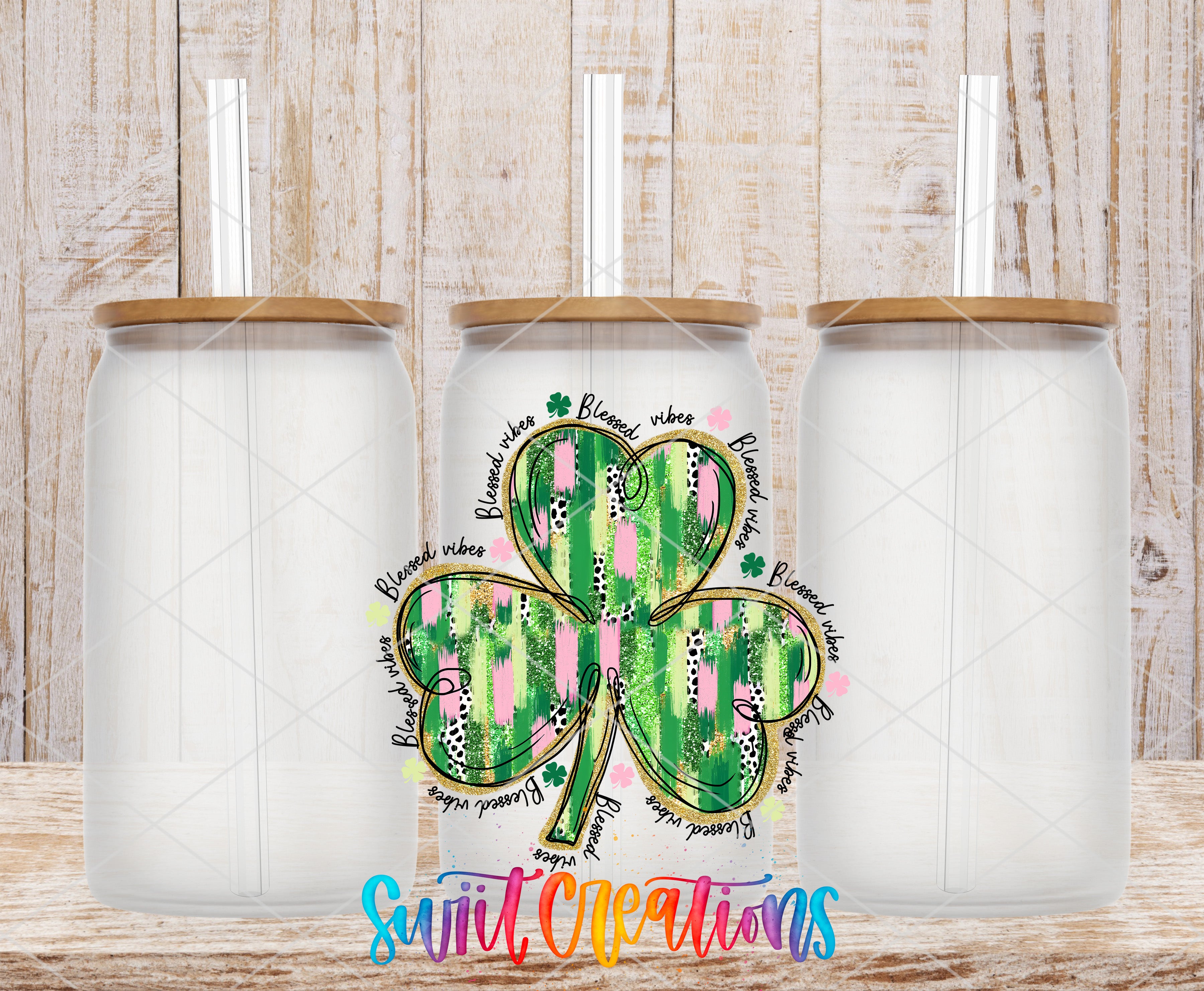 three white glass jars with brown lids, each with a straw sticking out of the top. In the center of the image, there is a colorful design of a shamrock, which is a type of clover, with various words and phrases written around it. The background of the image is a wooden surface with a textured appearance.