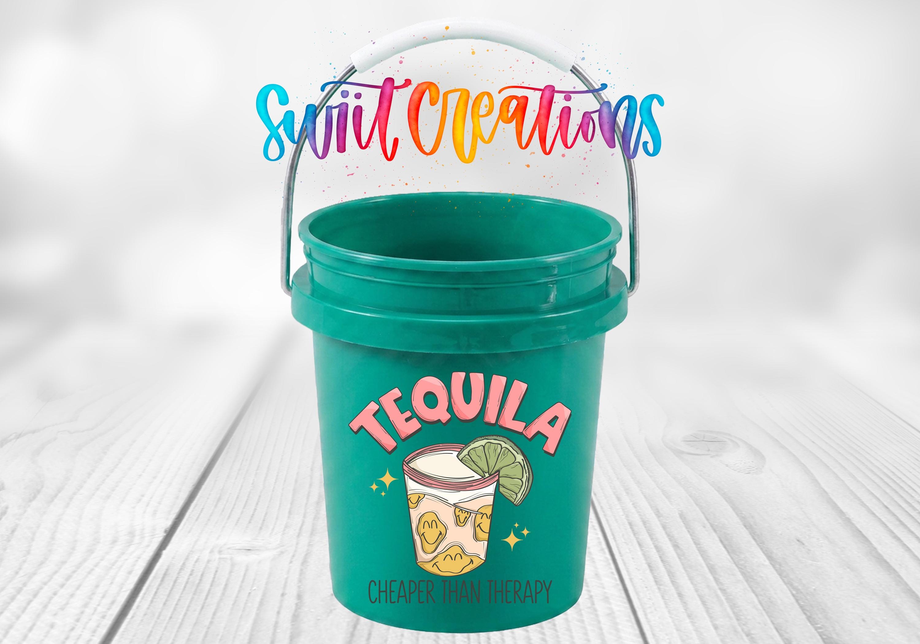 A green bucket with a tequila-themed design, featuring a tequila glass and a lime, along with the text "Tequila" and "CHEAPER THAN THERAPY".