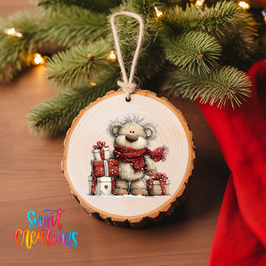 A wooden ornament featuring a teddy bear wearing a red scarf and holding presents, hanging on a Christmas tree.