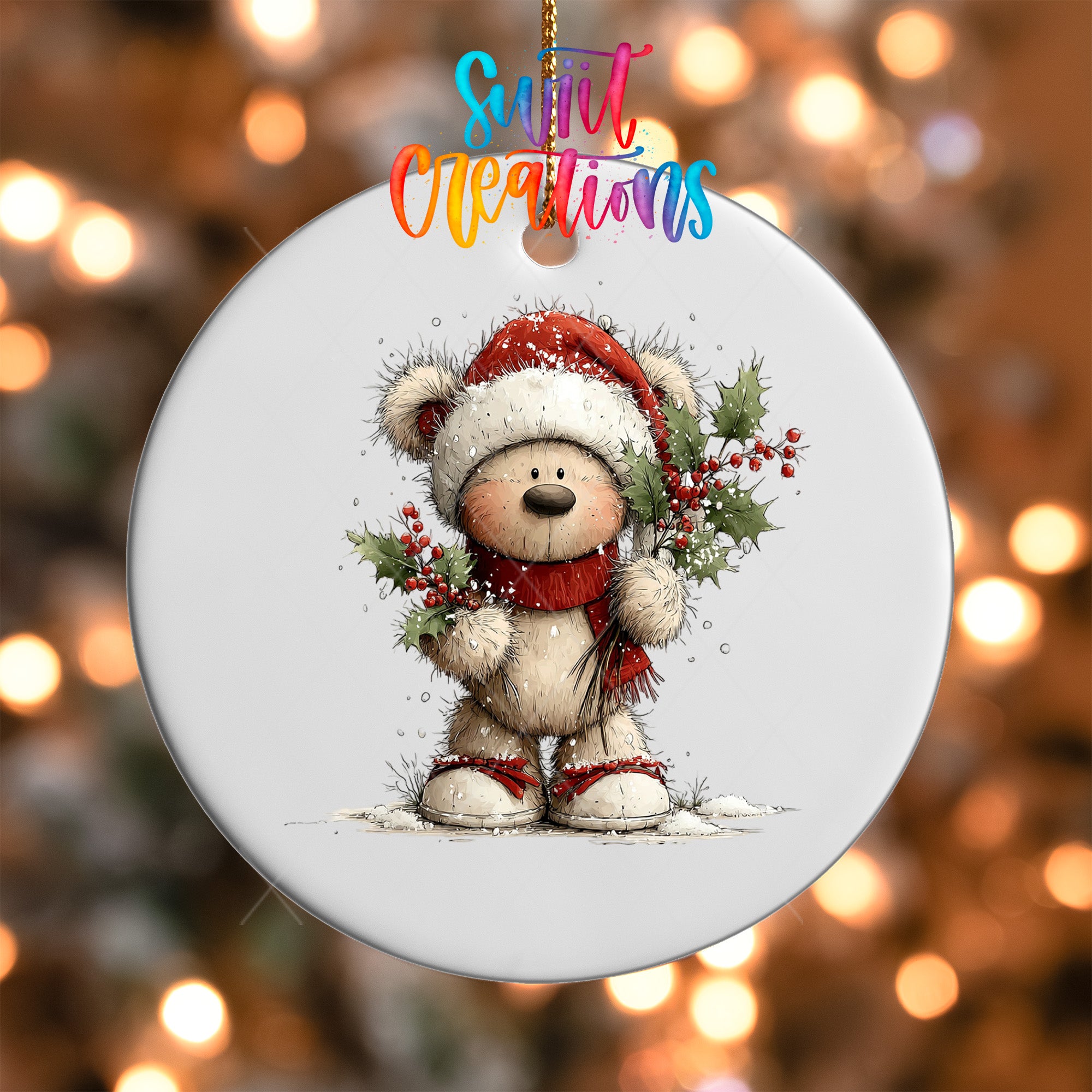A white ornament with a teddy bear wearing a Santa hat and holding holly and berries, set against a blurred background with Christmas lights.
