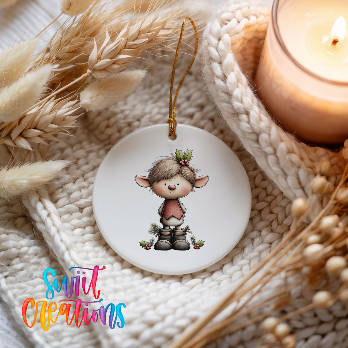 A white ceramic ornament featuring a cartoon elf with a holly leaf on its head, hanging on a white knitted blanket.