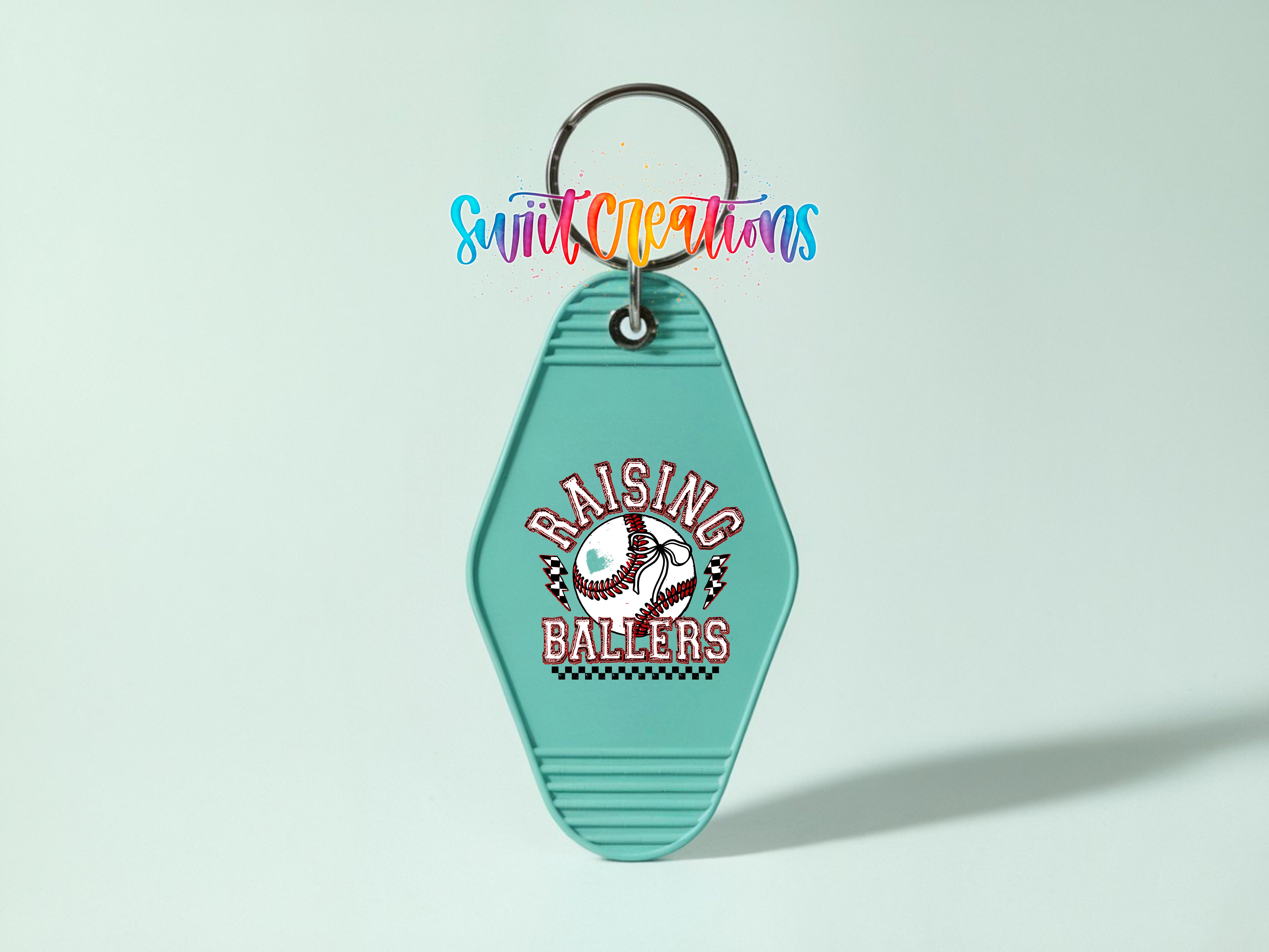 A turquoise keychain with the text "RAISING BALLERS" printed on it, along with a baseball graphic.