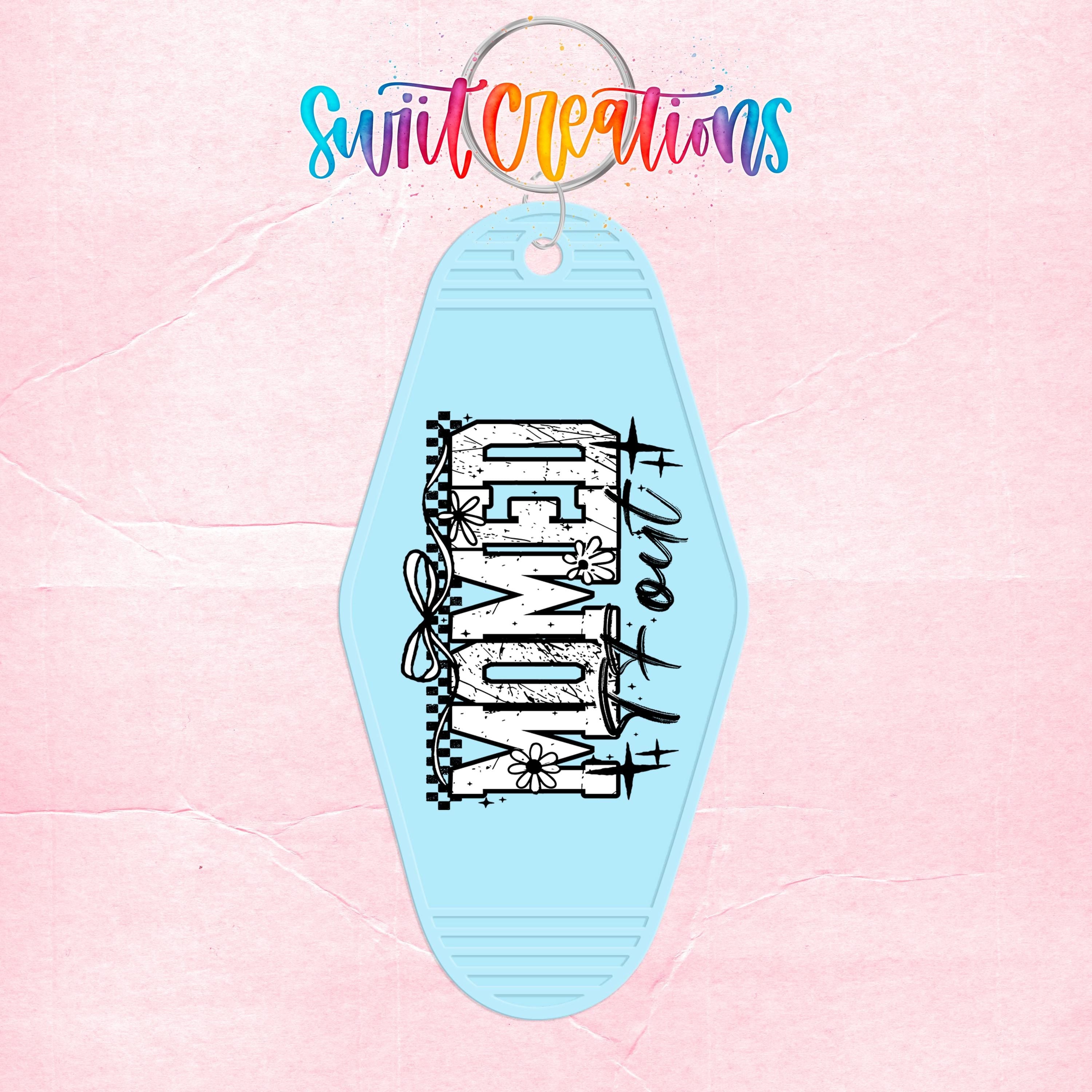 A blue keychain with the word "MOM" printed on it, set against a pink background with colorful text above it.