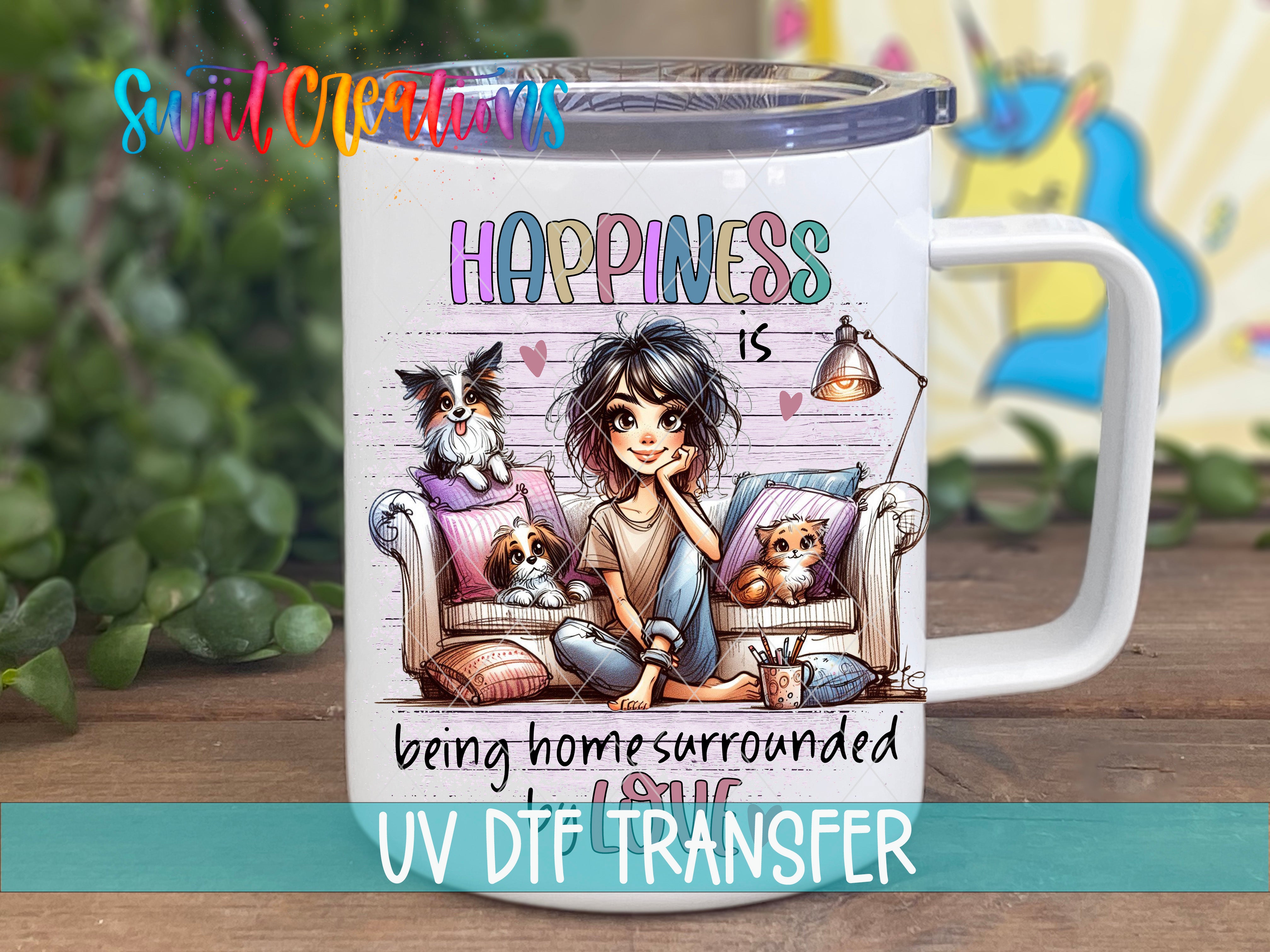 A white mug with a colorful illustration of a girl sitting on a couch with dogs, accompanied by the text "Happiness is being home surrounded by love" and "UV DFT TRANSFER".