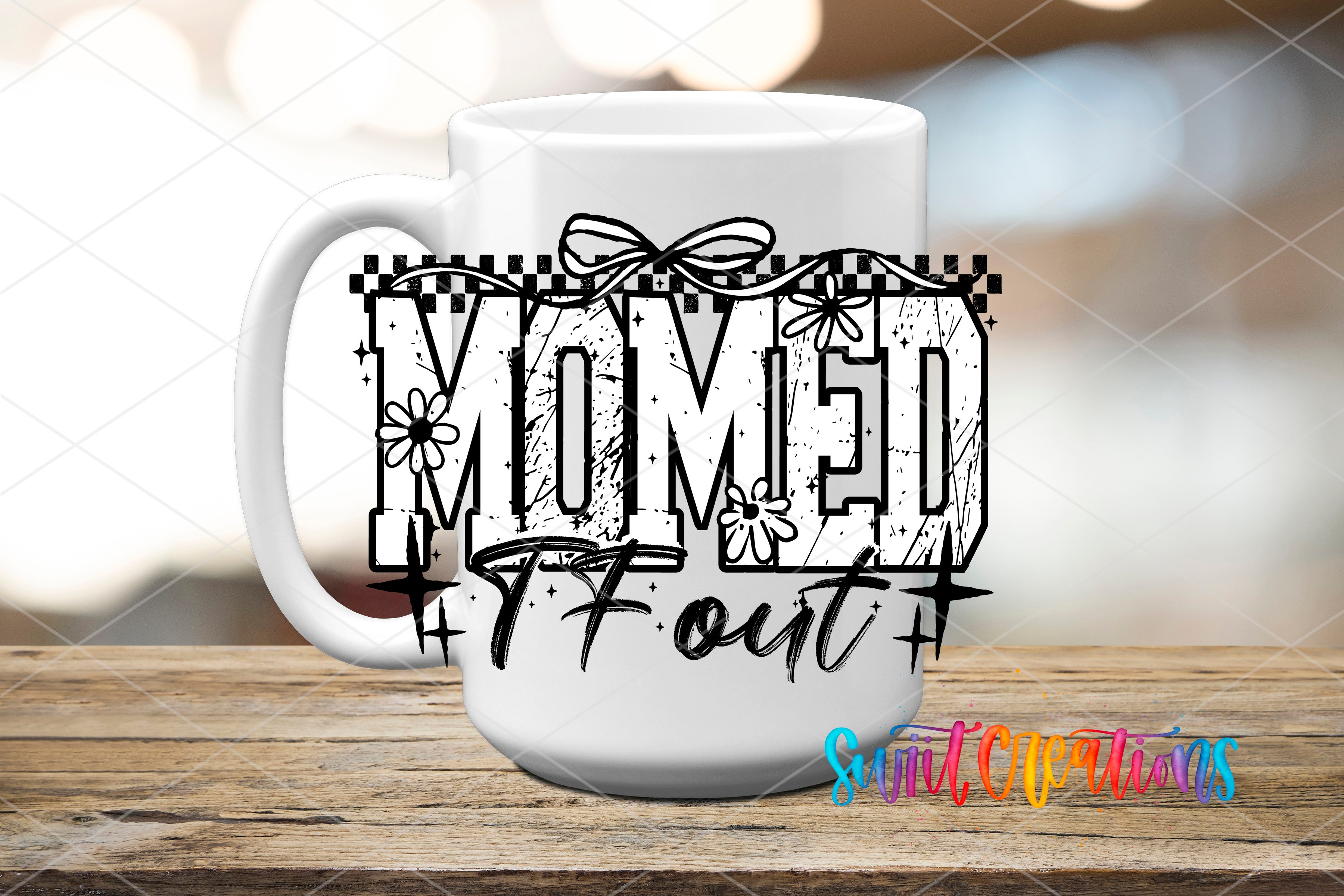 A white mug with the text "MOMED" and "7 out" printed on it, along with decorative elements such as flowers and stars.