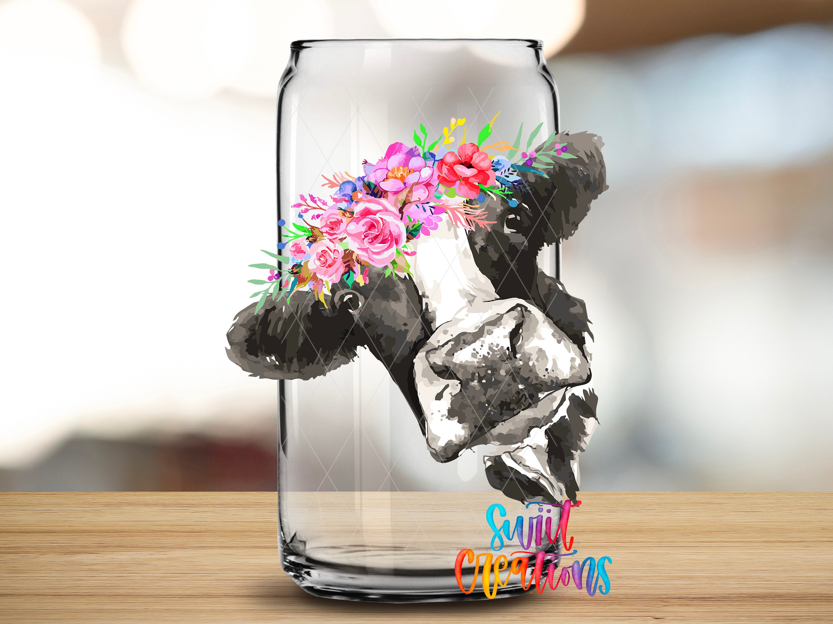 A glass can with a floral design on it, placed on a wooden surface.