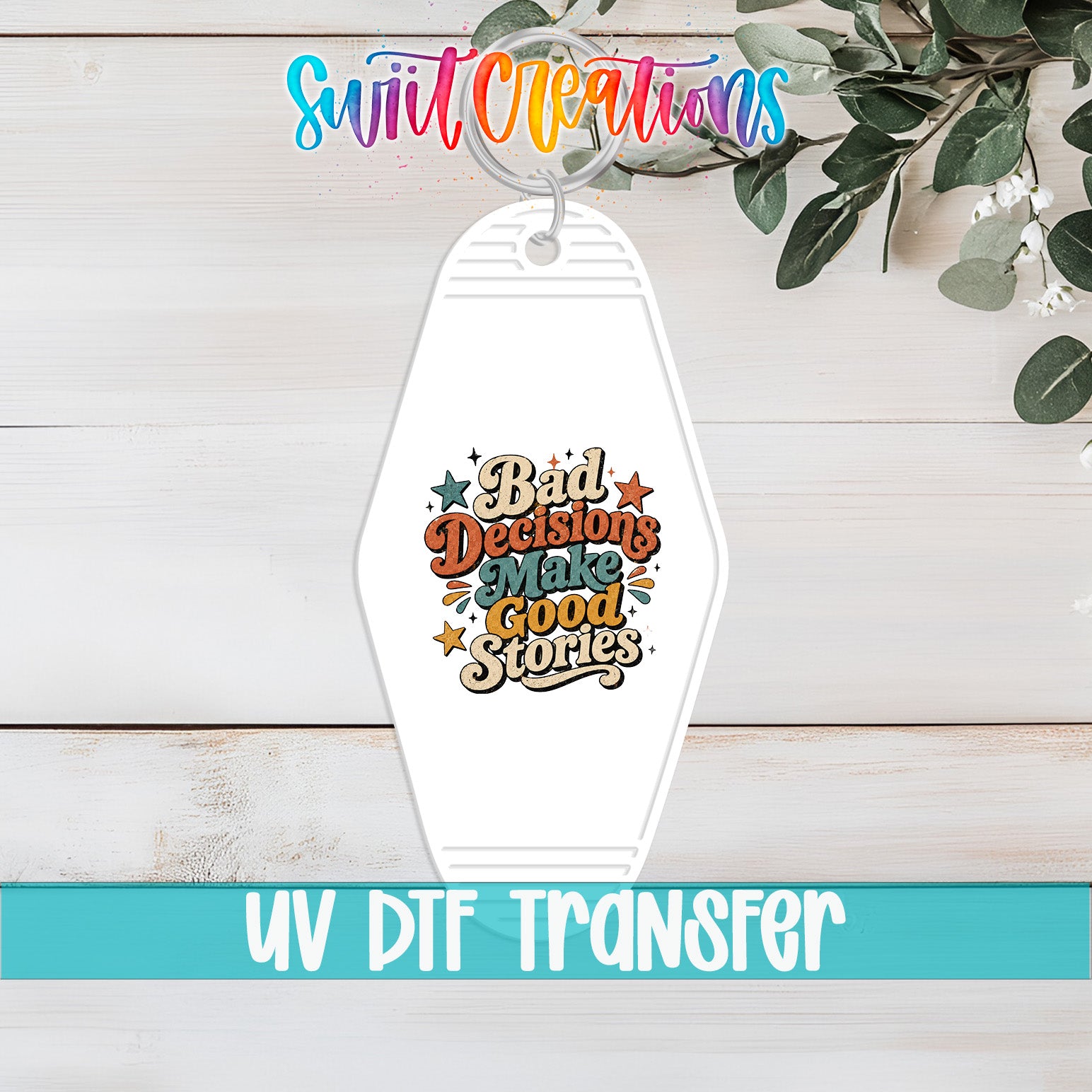 A keychain with a colorful graphic design and text, placed on a wooden surface with some greenery in the background.