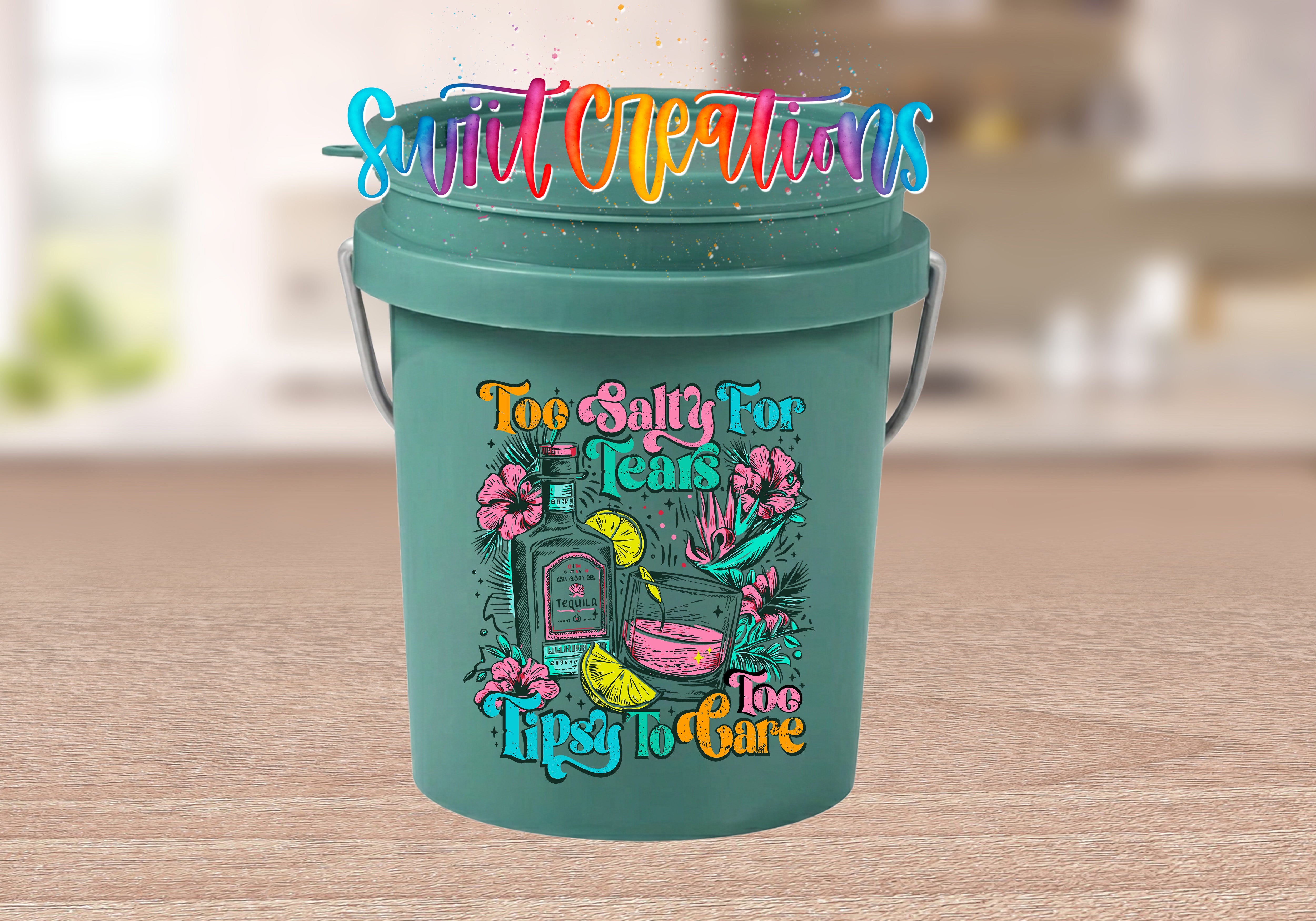 A green bucket with a colorful graphic design featuring a bottle, flowers, and text that reads "Too Salty for Tears Tipsy to Care".