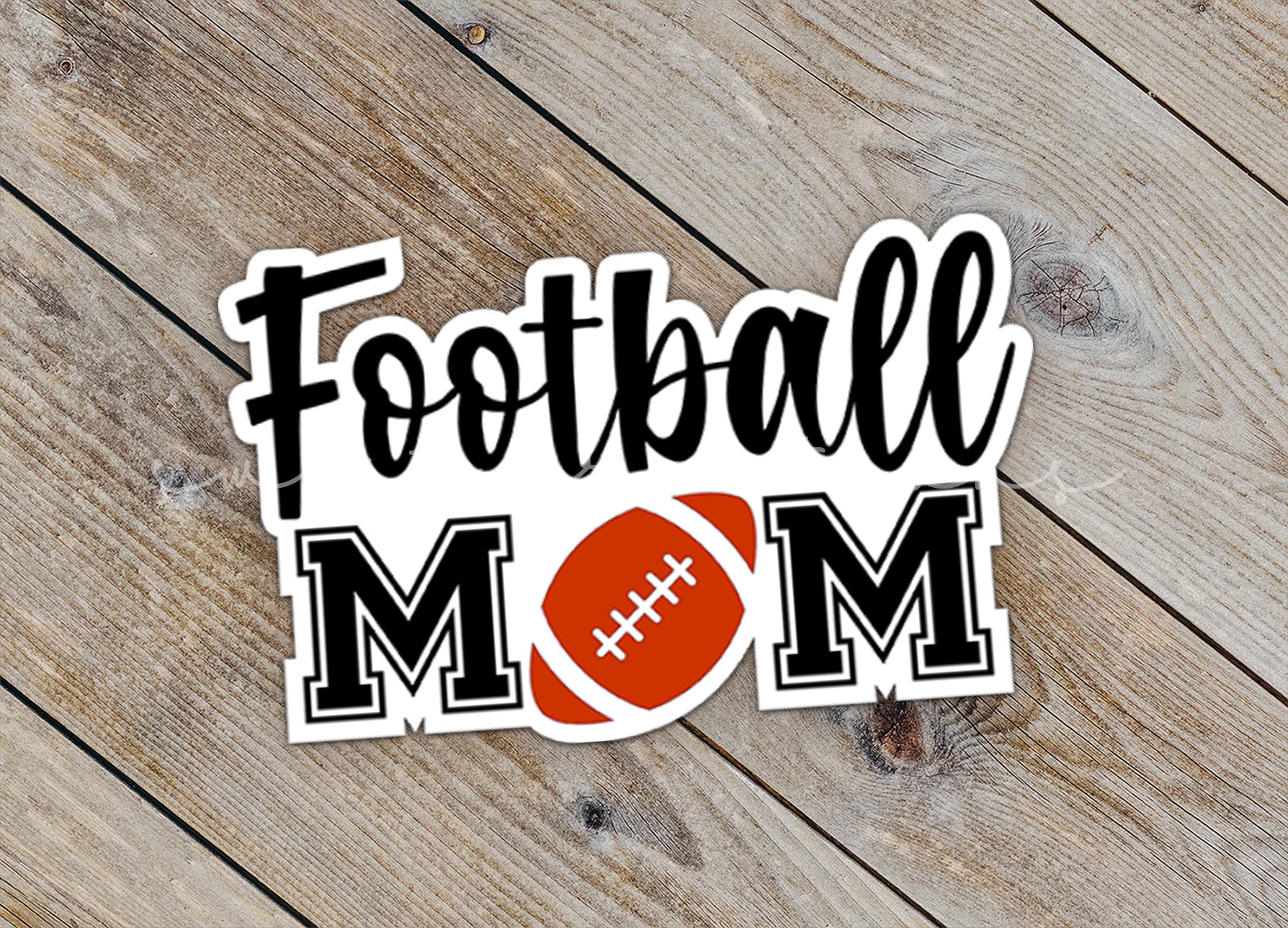a football mom sticker sitting on top of a wooden table
