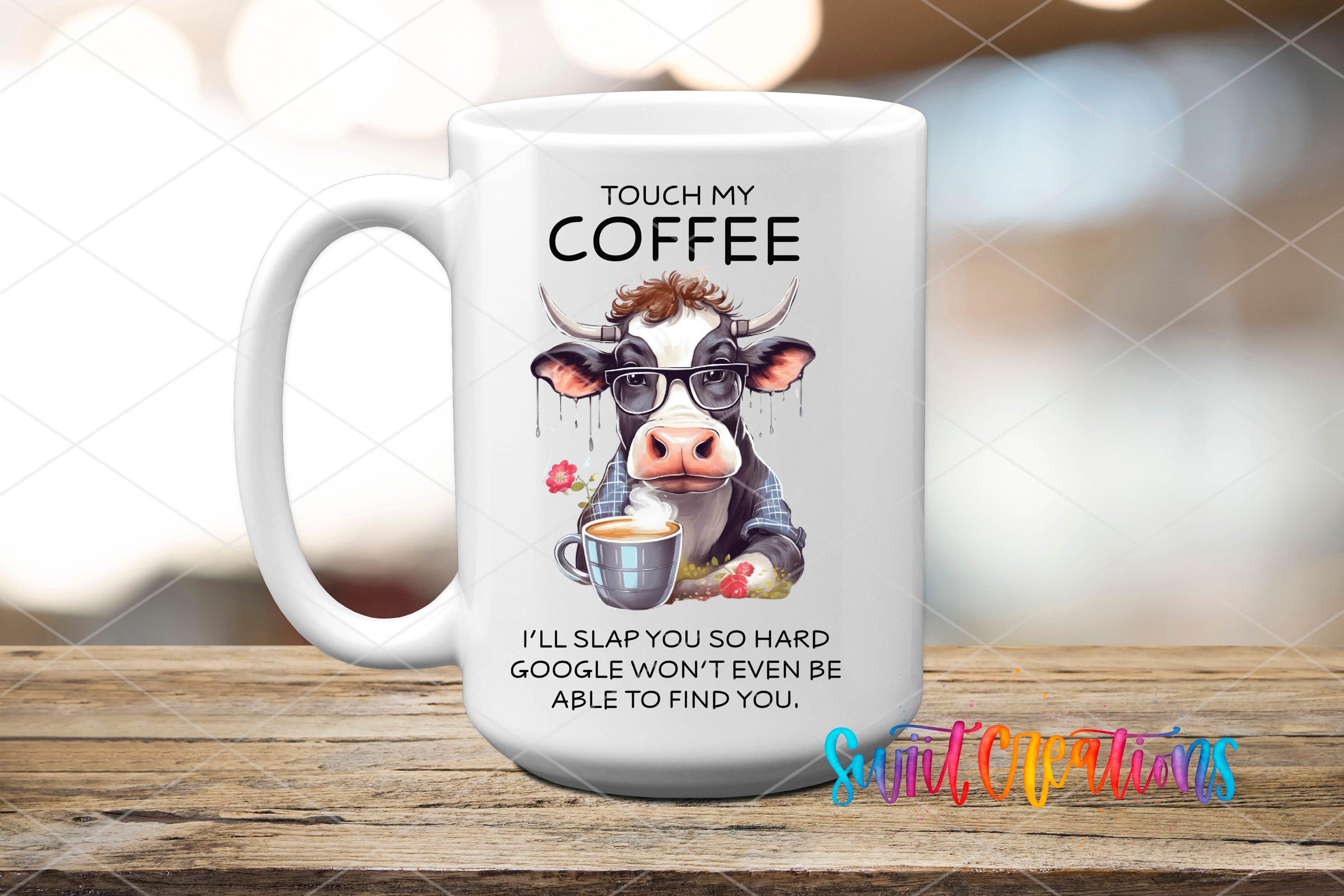 A white coffee mug with a cartoon cow and text on it, placed on a wooden surface.