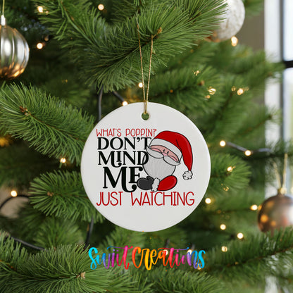A white Christmas tree ornament with a Santa Claus image and text that reads "What's poppin? Don't mind me just watching".