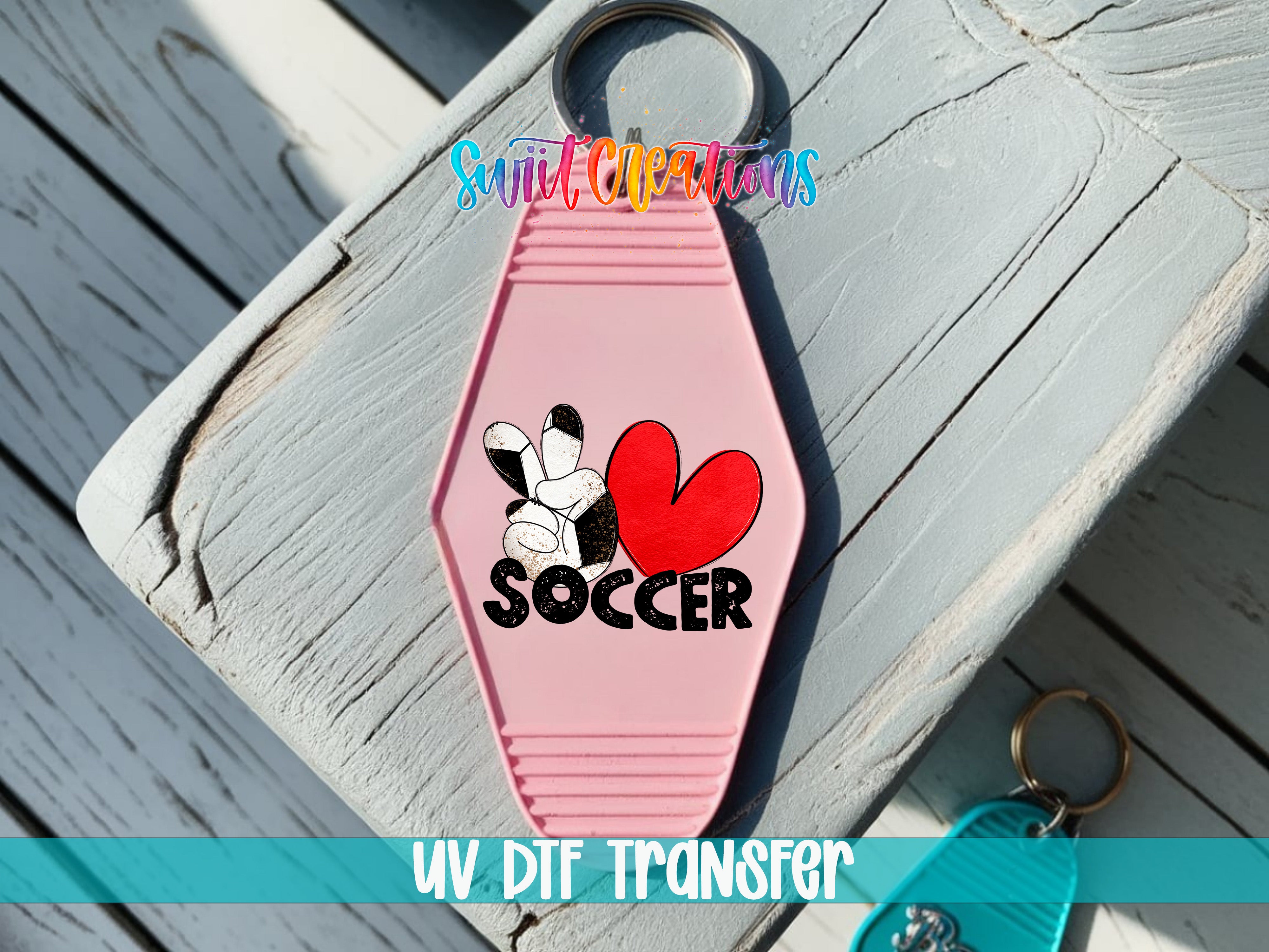 A pink keychain with a heart and soccer ball design, along with the text "SOCCER" and "UV DIF TRANSFER".