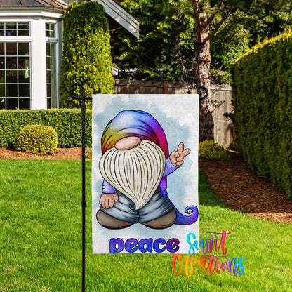 A colorful garden gnome sign with the word "Peace" written below it, set against a backdrop of a well-maintained lawn and trees.