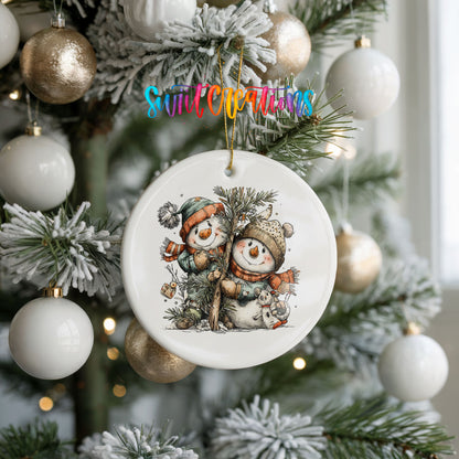 A Christmas tree decorated with ornaments, including a white ornament featuring two snowmen.