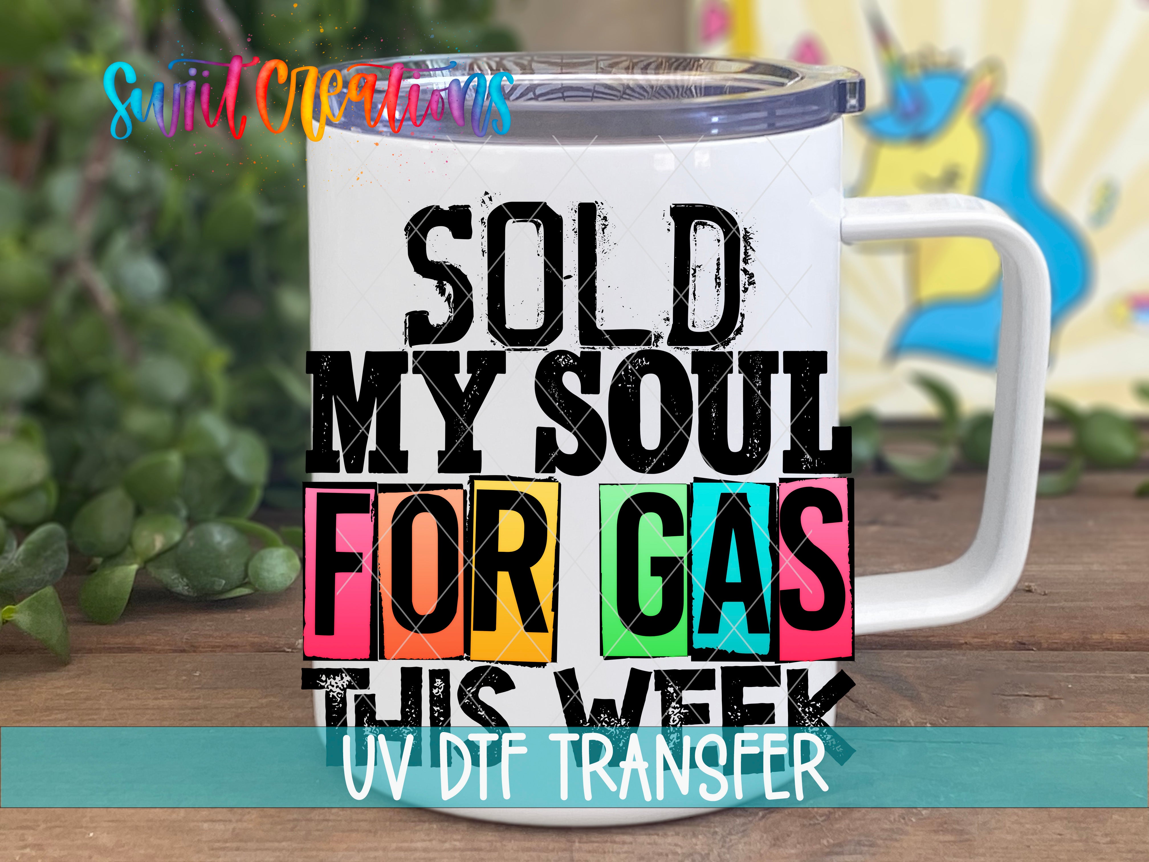 A white mug with a colorful graphic design on it, featuring text that says "SOLD MY SOUL FOR GAS THIS WEEK UV DDF TRANSFER".