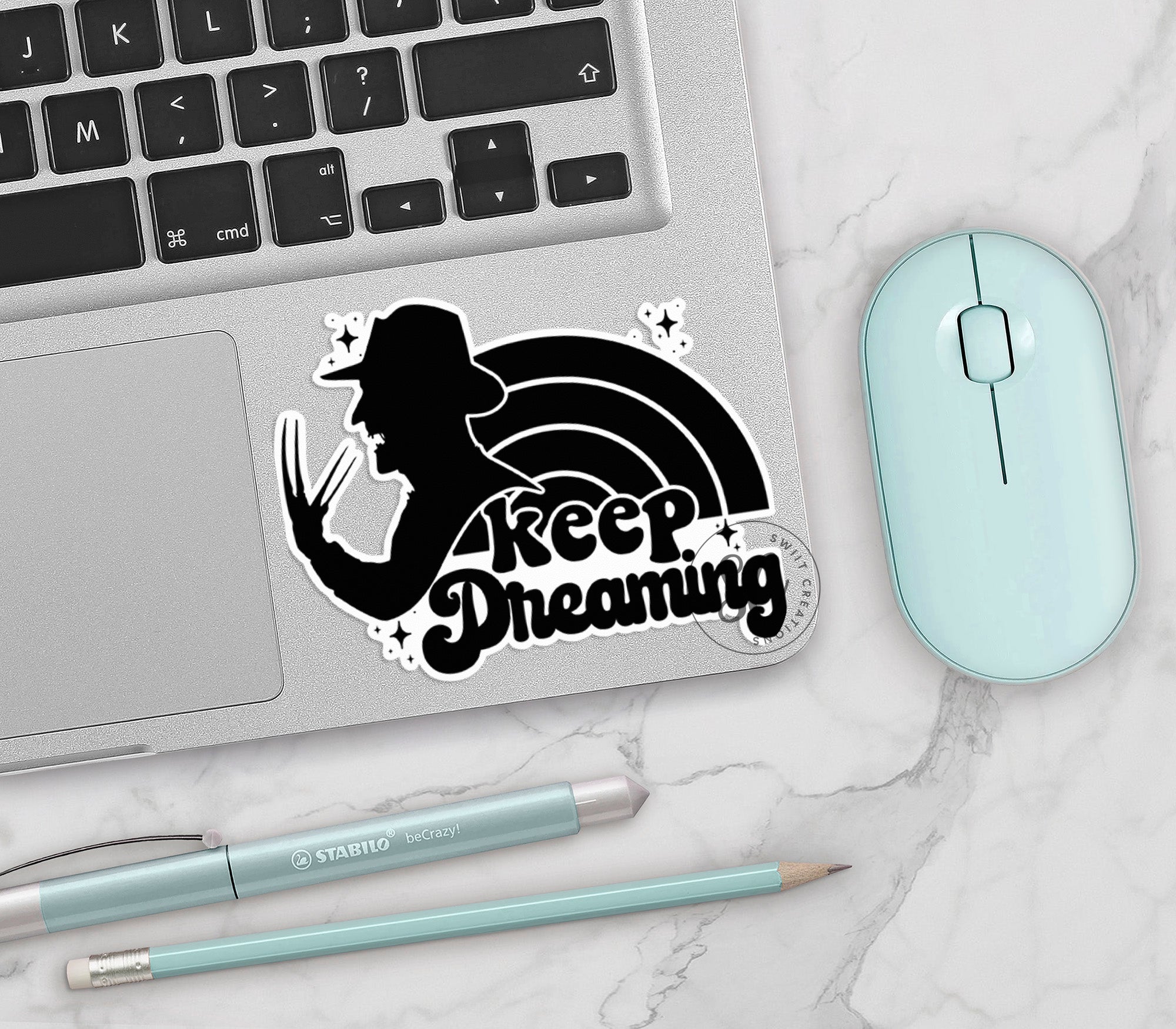 a sticker that says keep dreaming next to a laptop