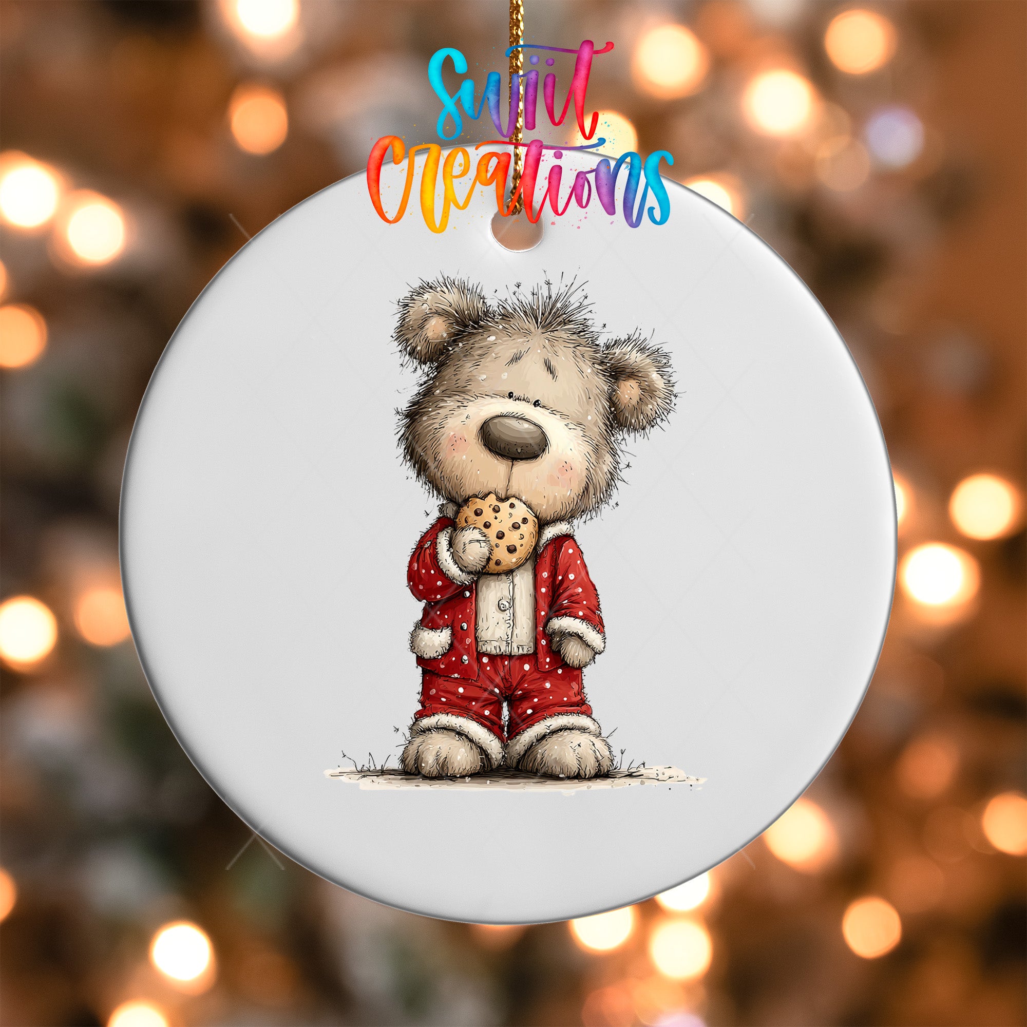 A white ornament featuring a cartoon teddy bear wearing a red outfit and holding a cookie.