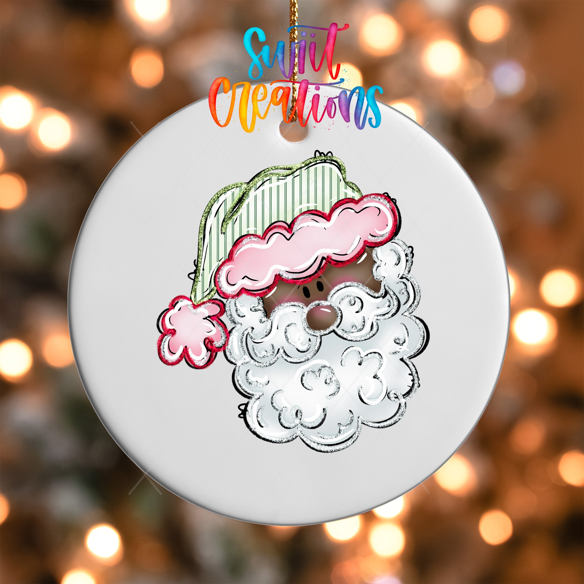 A white ornament with a cartoon Santa Claus face and a pink hat is hanging against a background of colorful lights.