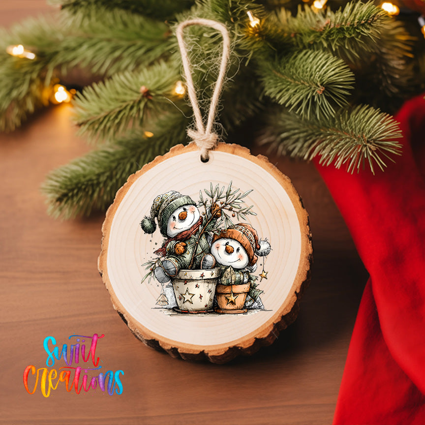 A wooden ornament with a snowman and a potted plant, hanging on a Christmas tree.