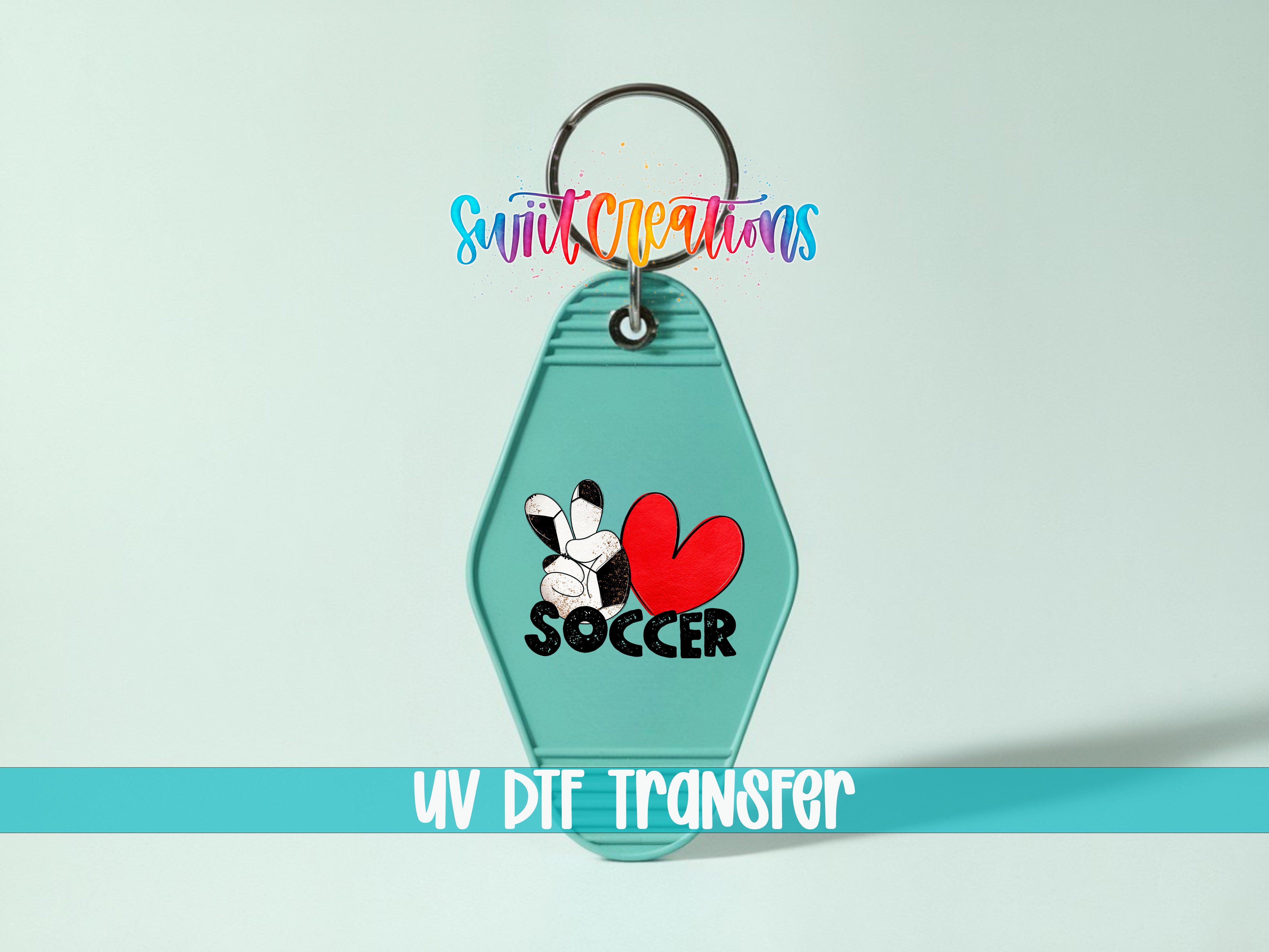 A keychain with a soccer-themed design, including a heart and the word "SOCCER". The keychain is set against a light blue background, and there is text at the bottom of the image that reads "UV DIF TRANSFER".