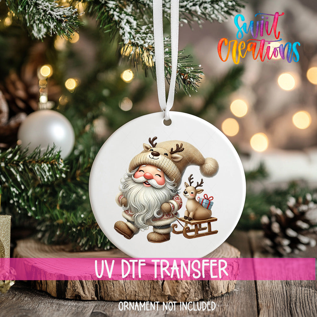 A white ornament with a Santa Claus and reindeer design hangs on a Christmas tree, surrounded by pine branches and twinkling lights.