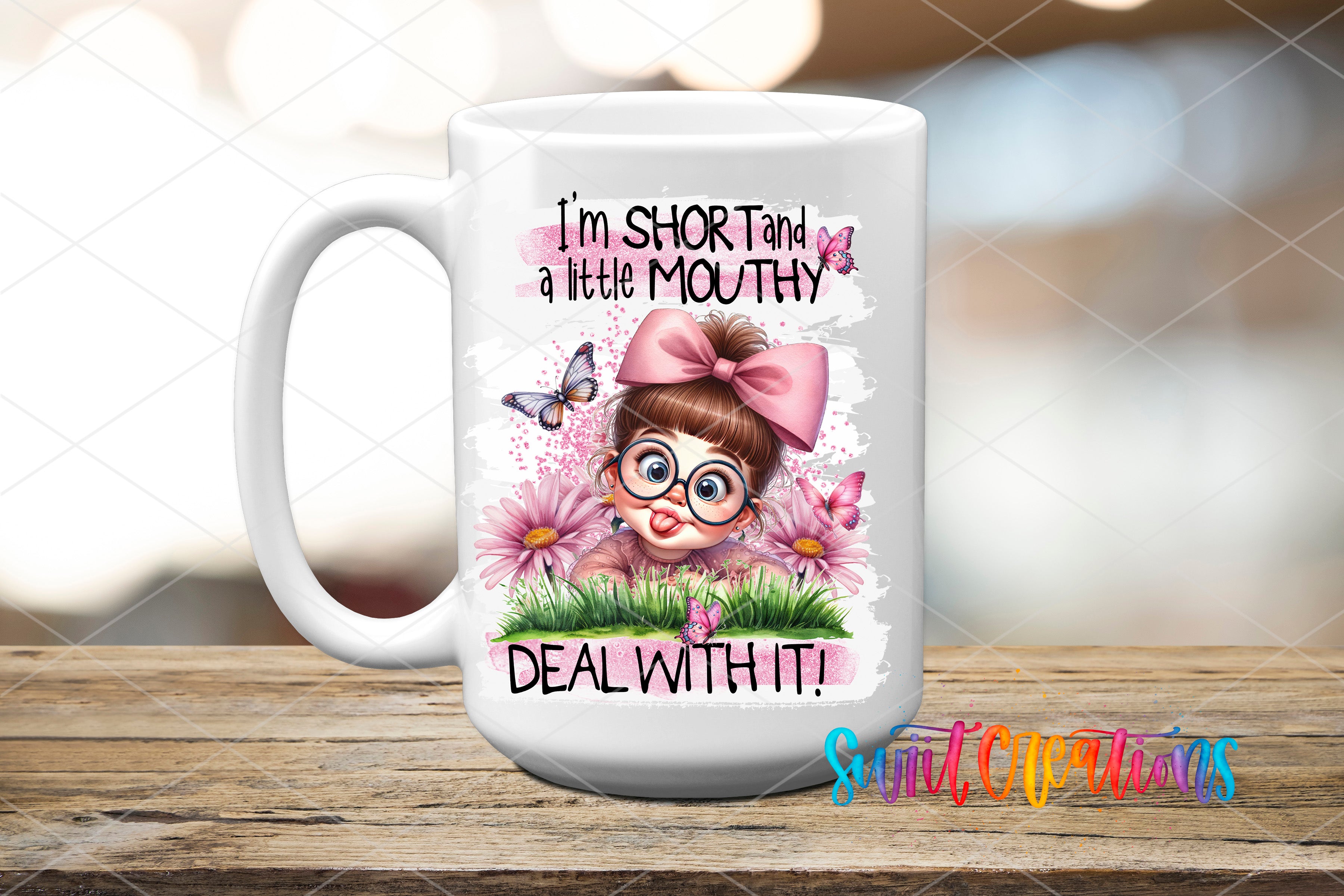A white ceramic mug with a cartoon illustration of a young girl with glasses and a pink bow, surrounded by flowers and butterflies. The text on the mug reads "I'm short and a little mouthy, deal with it!"