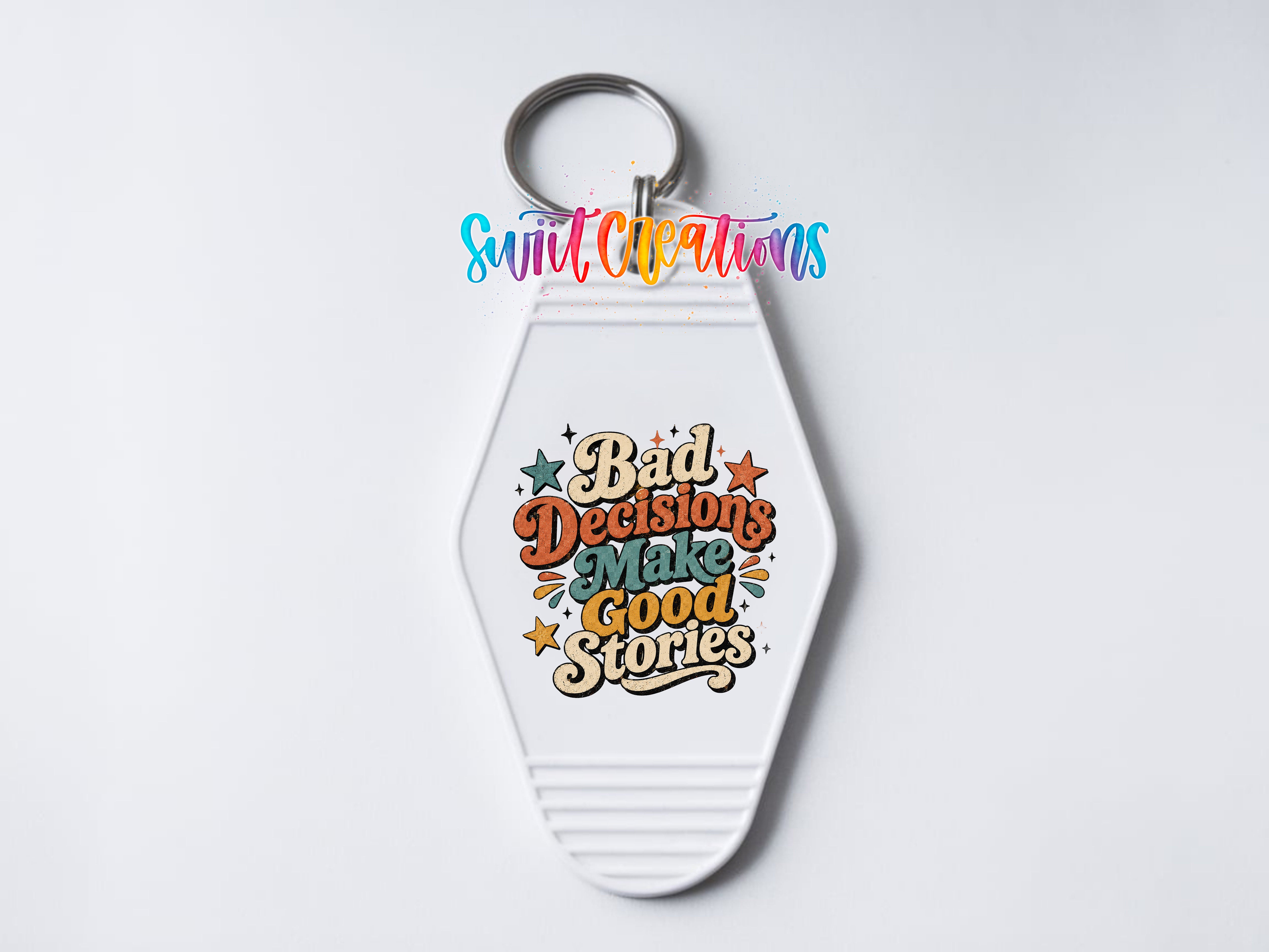 A keychain with a colorful design featuring the text "Bad Decisions Make Good Stories" and a decorative star pattern.