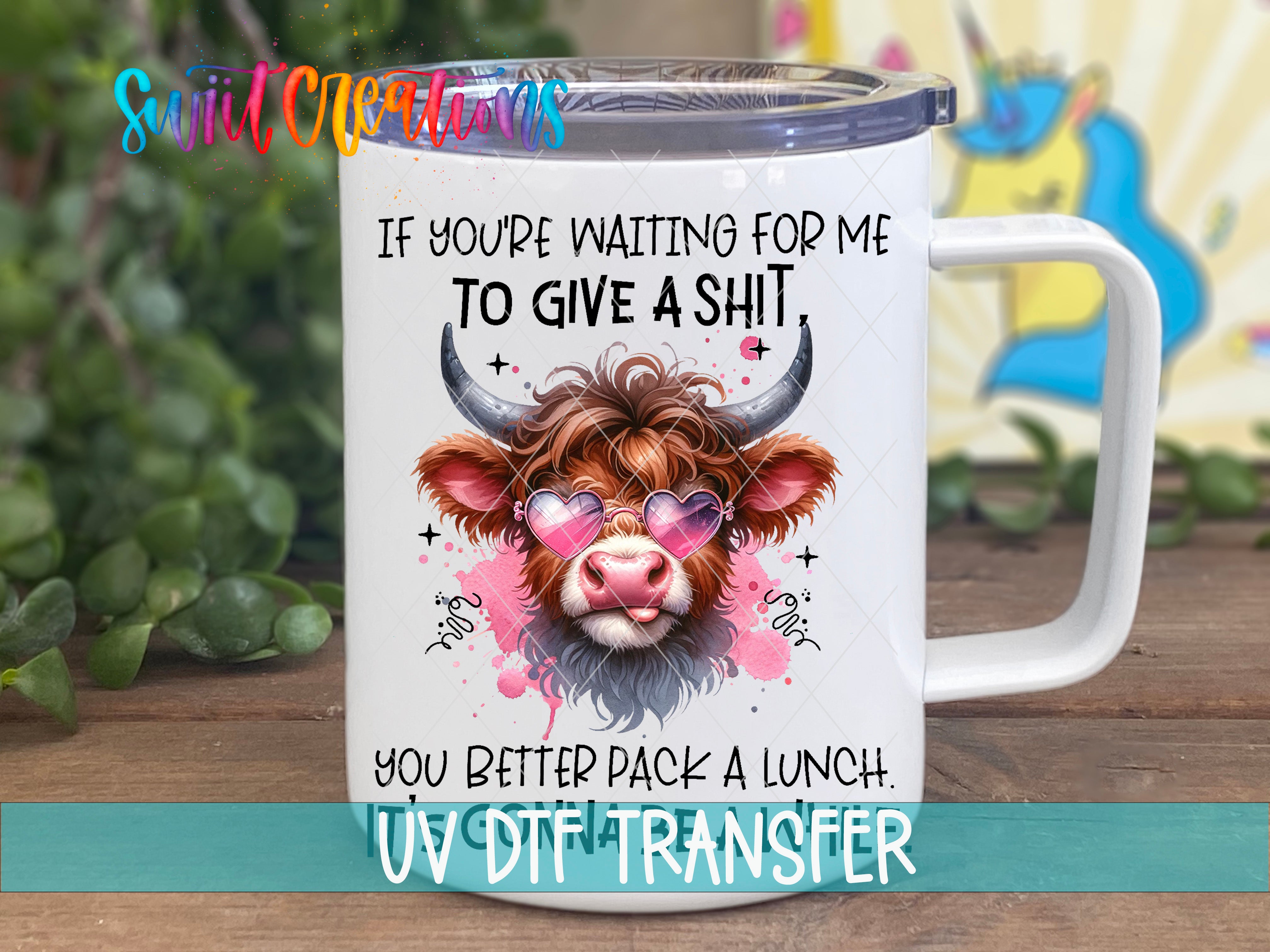 A mug with a cartoon cow wearing sunglasses and a hat, along with text that reads "If you're waiting for me to give a shit, you better pack a lunch. UV Dtf Transfer".