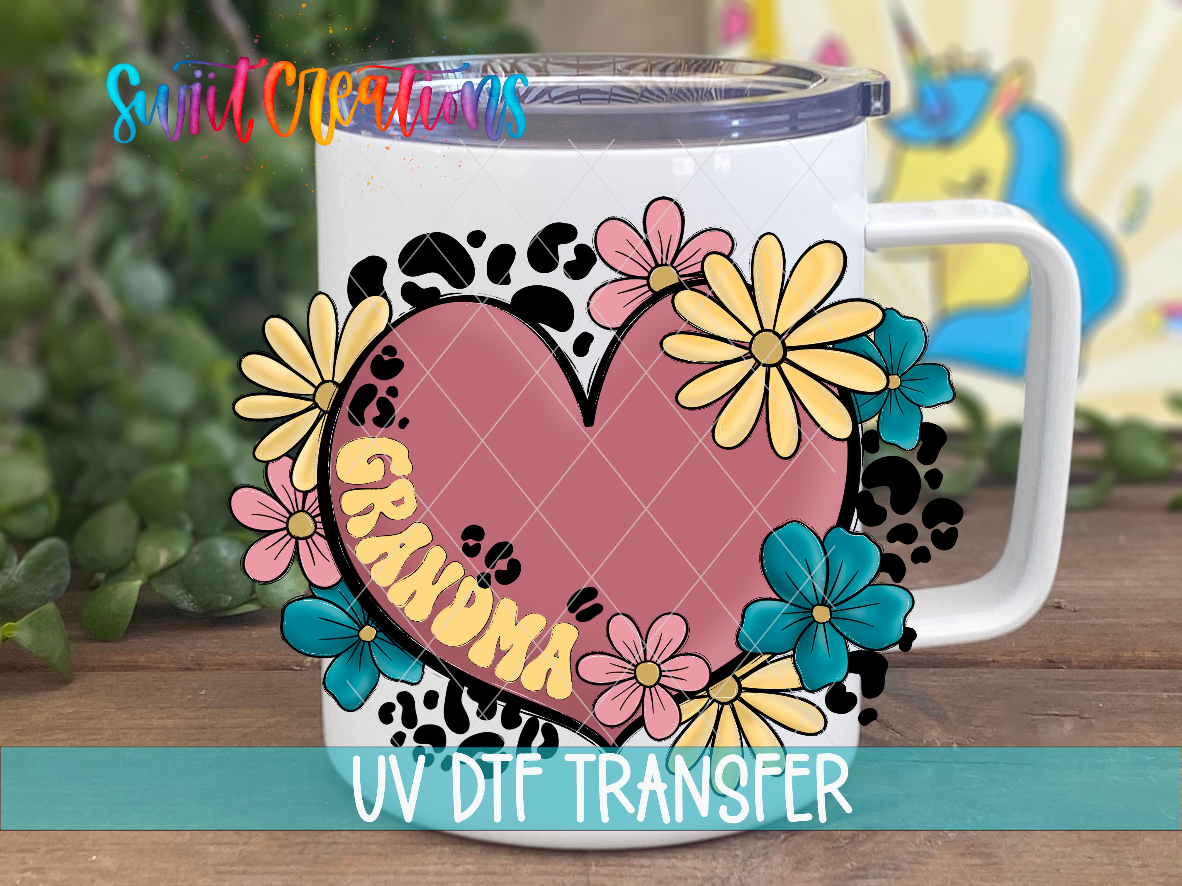 A white mug with a heart-shaped design featuring colorful flowers and the word "GRANDMA" printed on it.