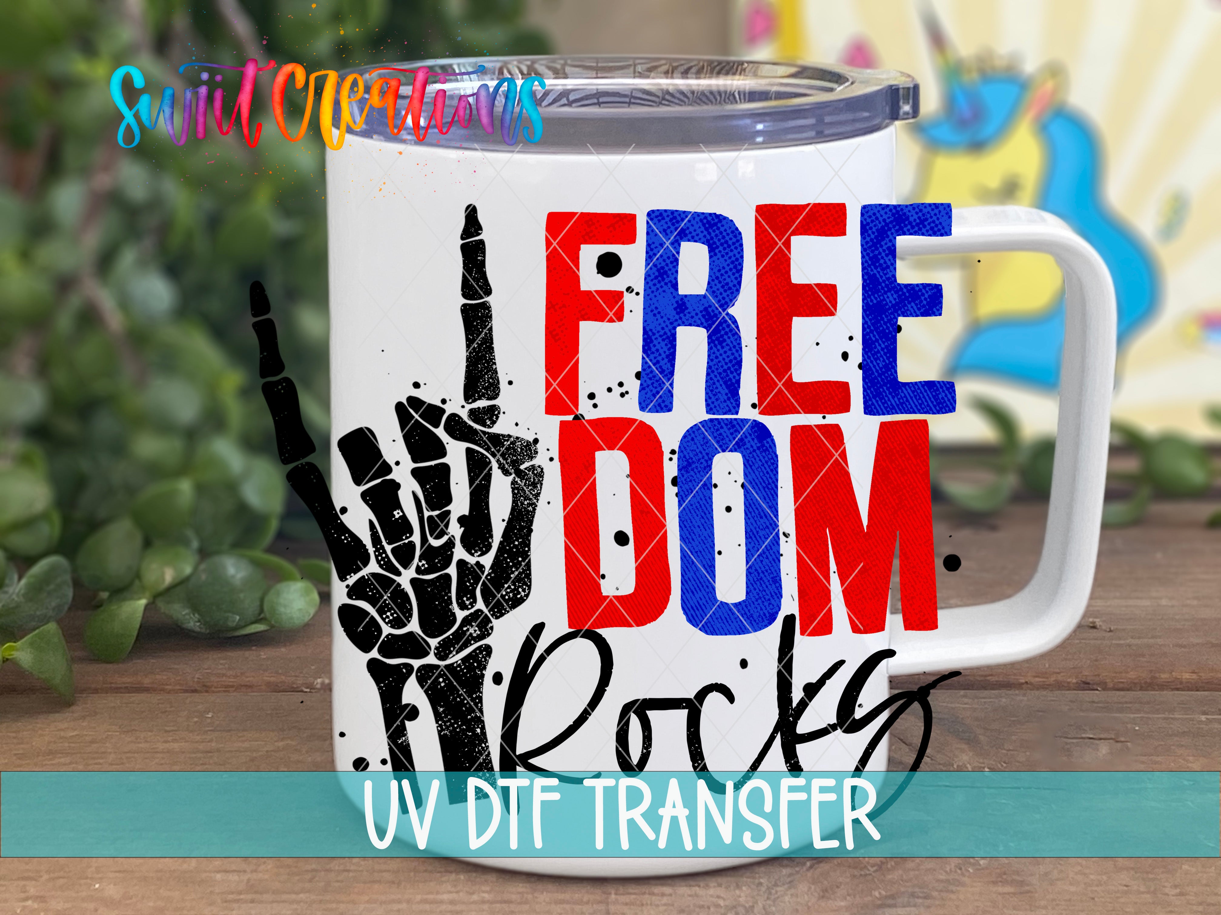A white mug with a graphic design featuring the text "FREE" in red, "DOM" in blue, and "ROCKS" in black, along with a skeleton hand gesture.