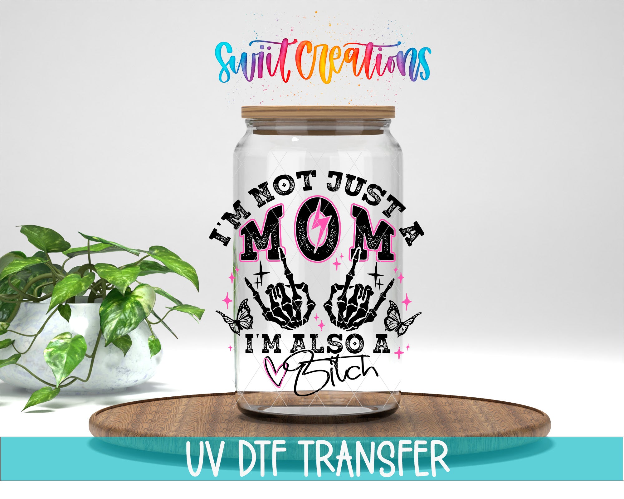 A glass jar with a printed design on it, placed on a wooden surface. The jar has a lid and is surrounded by a potted plant.