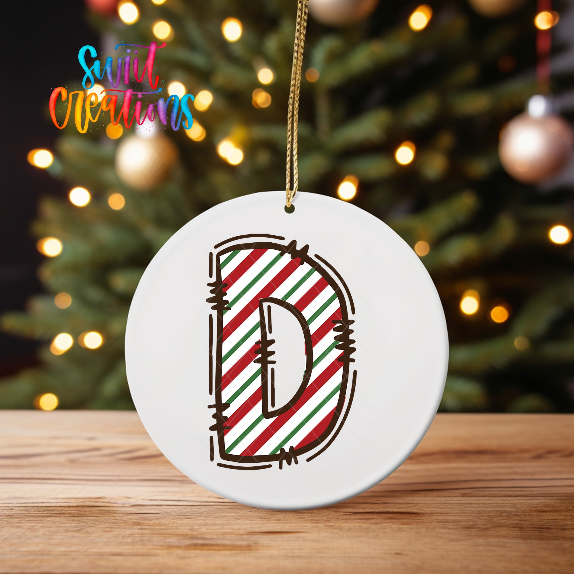 A white circular ornament with a large letter "D" in red, green, and white stripes is hanging from a string.