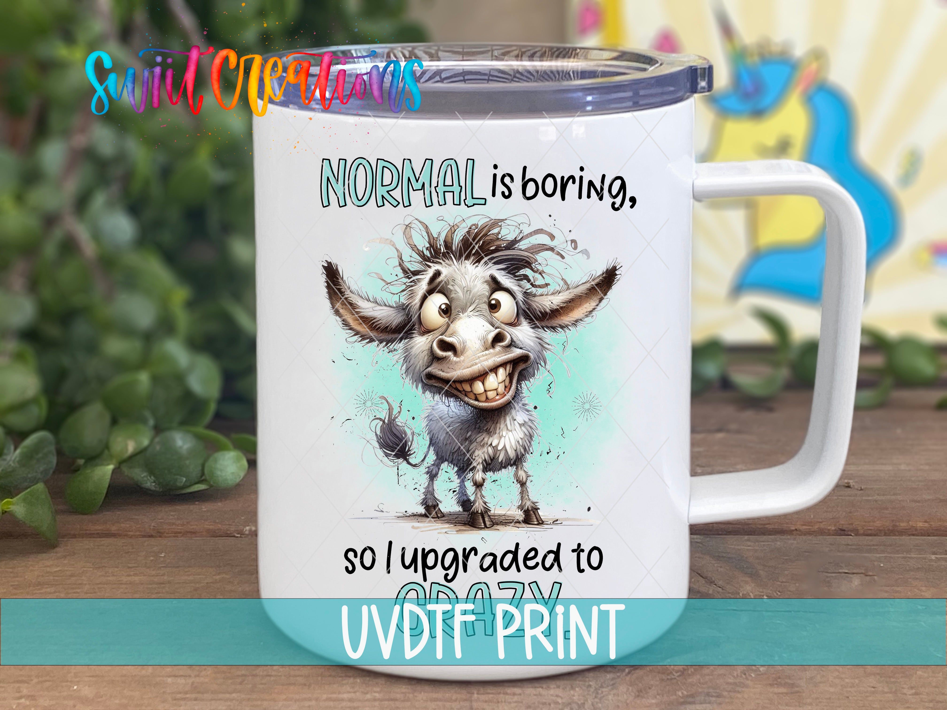 A white mug with a cartoon donkey and text that says "NORMAL is boring, so I upgraded to UVDT print".