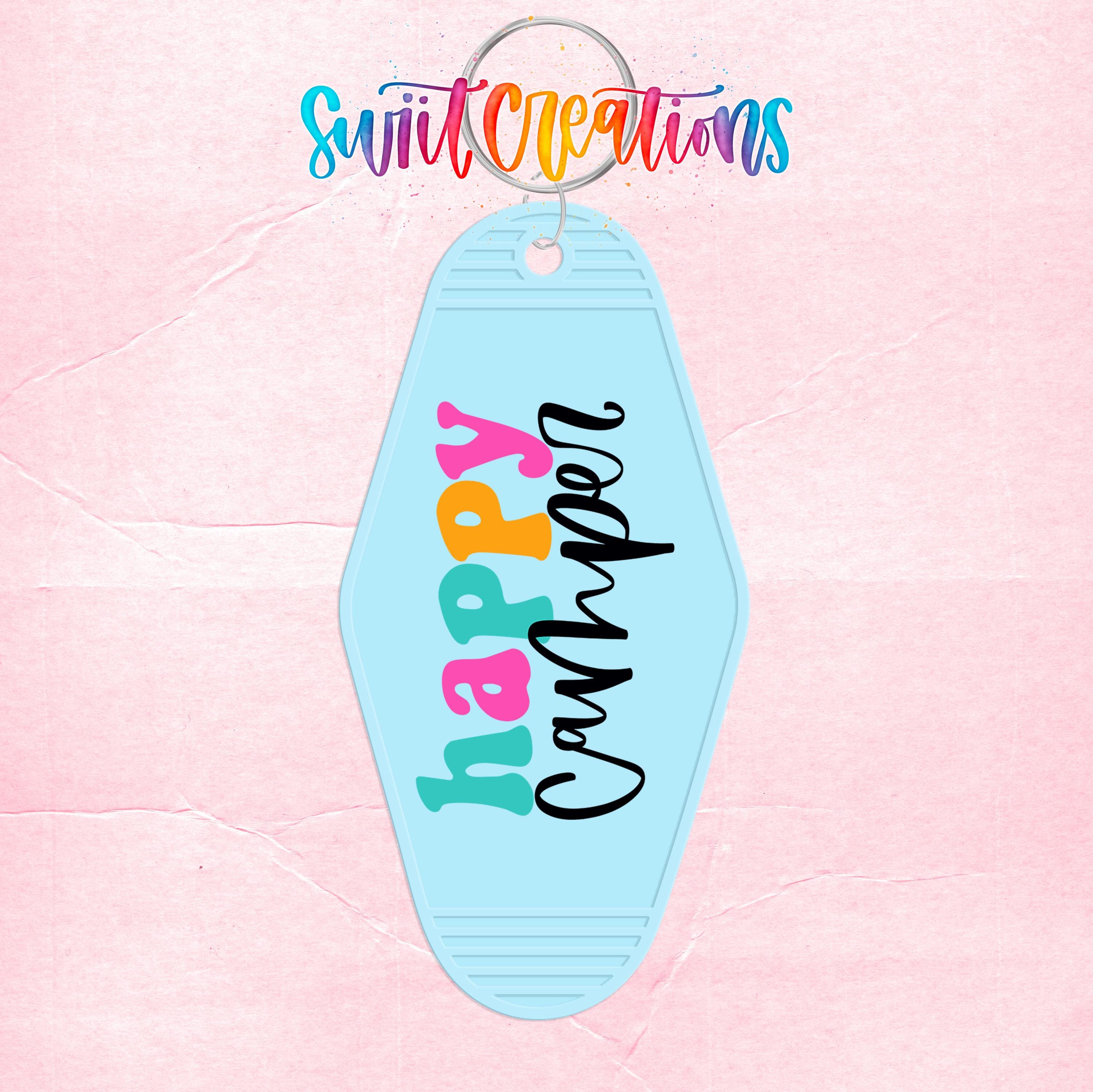 A keychain with the text "Happy Camper" printed on it, set against a pink background.