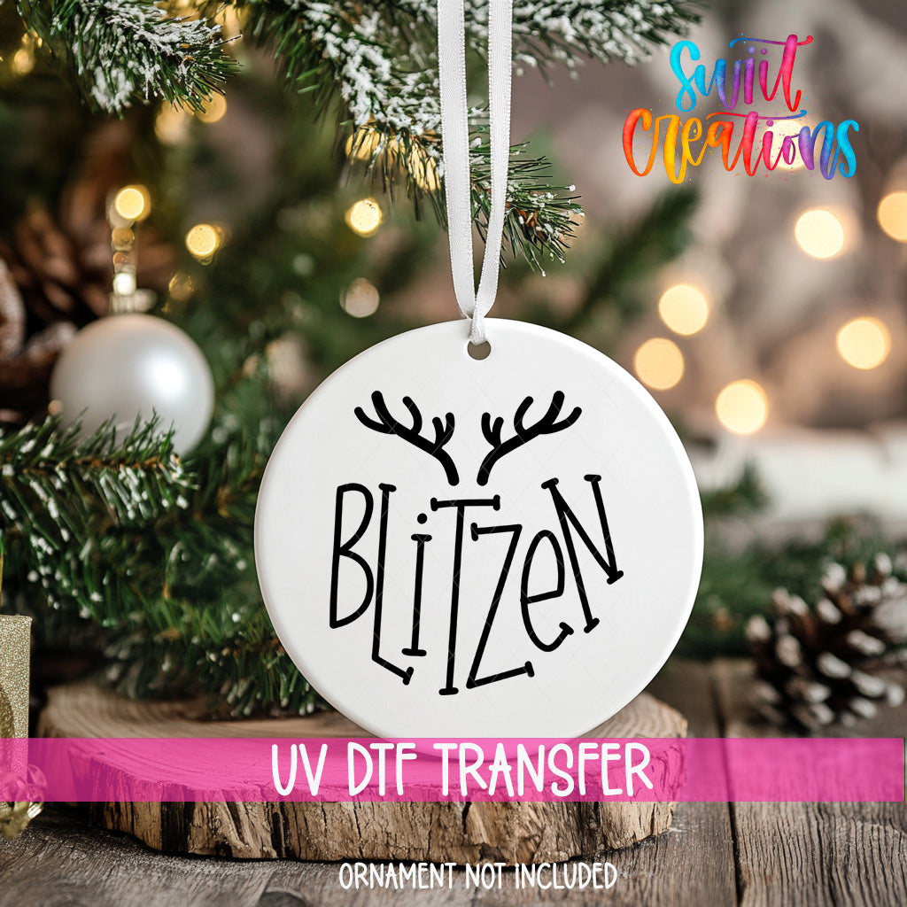 A white ornament with the word "Blitzen" printed on it, hanging from a Christmas tree.