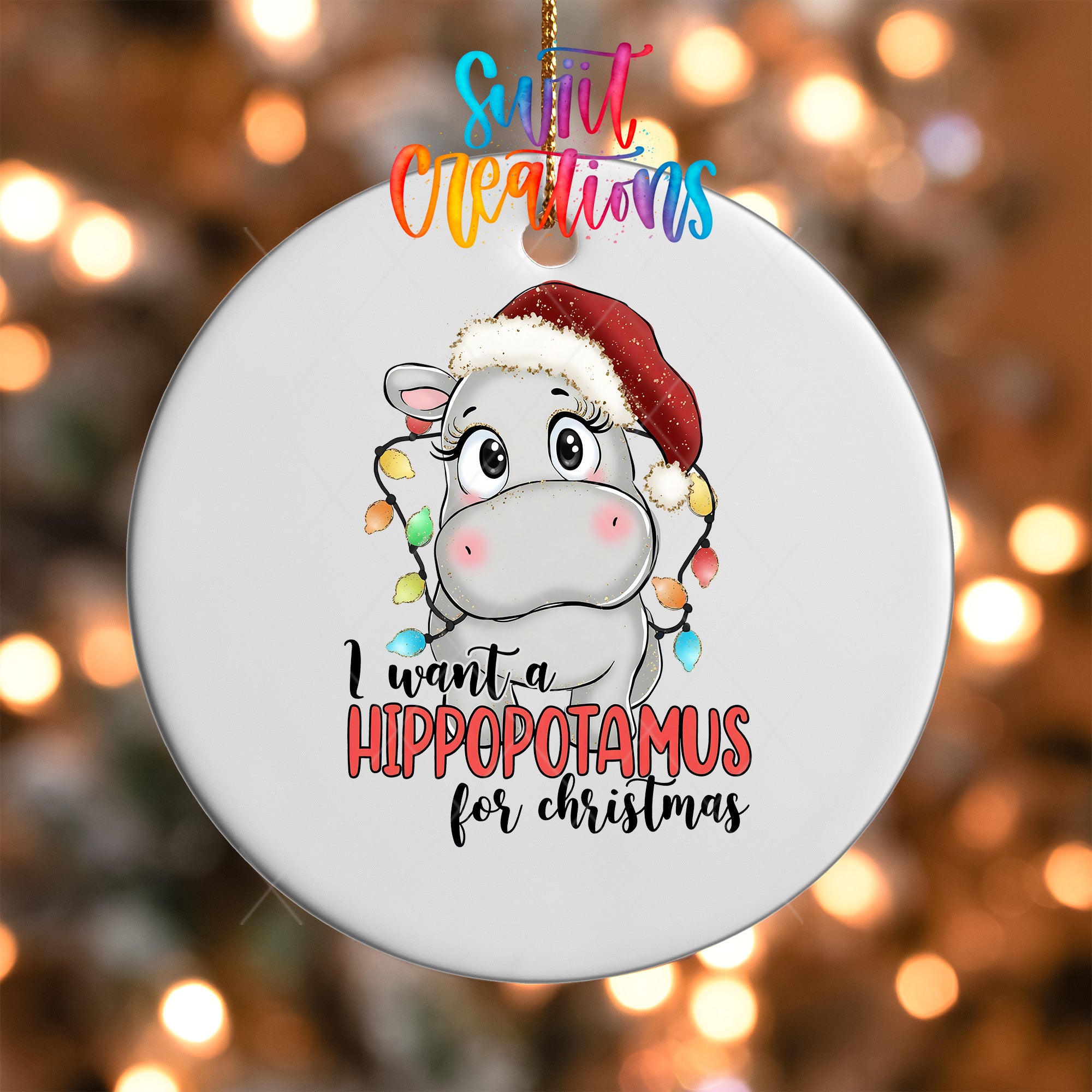 A white ornament with a cartoon image of a hippopotamus wearing a Santa hat and the text "I want a hippopotamus for Christmas"