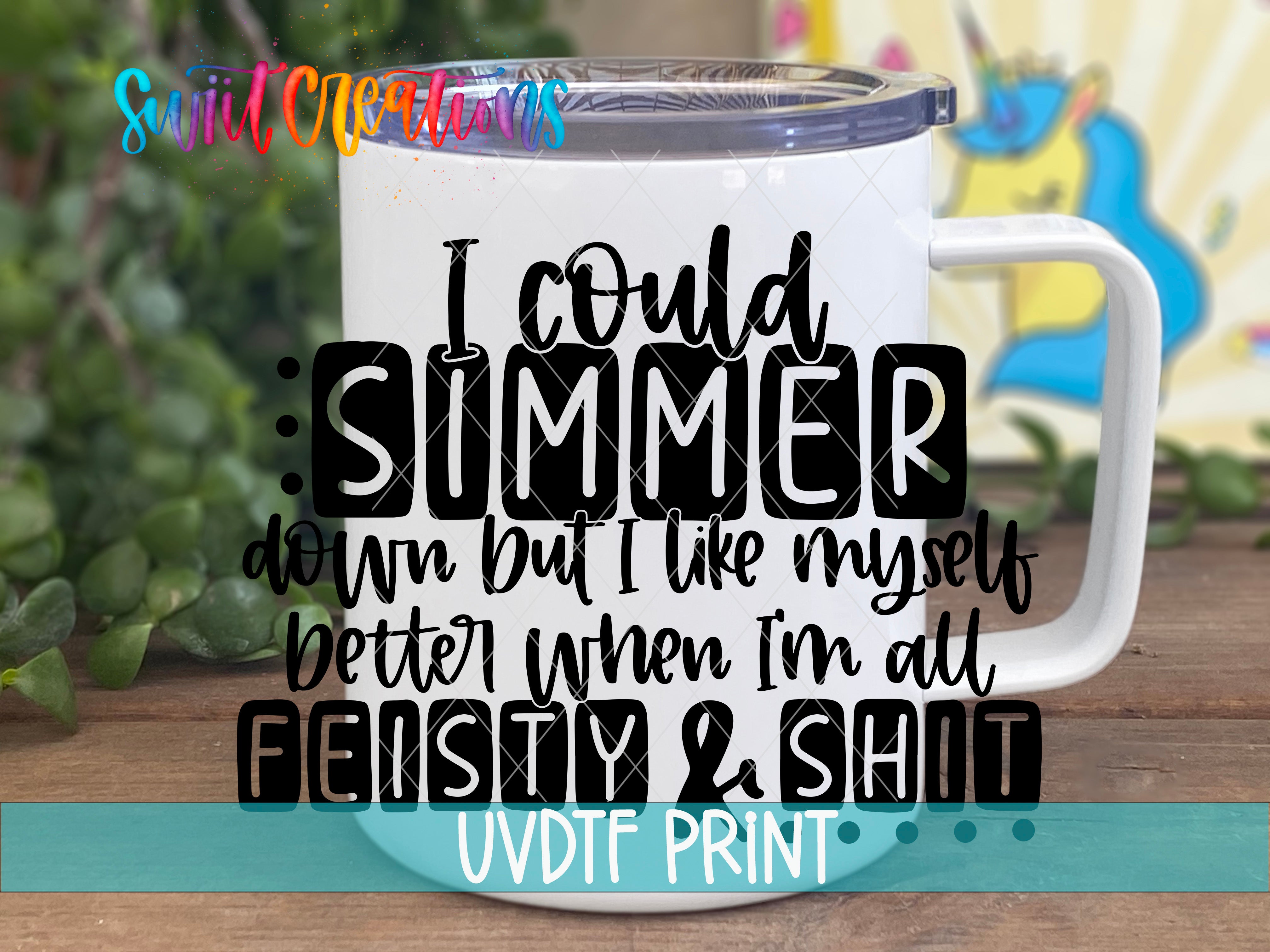 A white mug with a printed text design on it, placed on a wooden surface with greenery in the background.