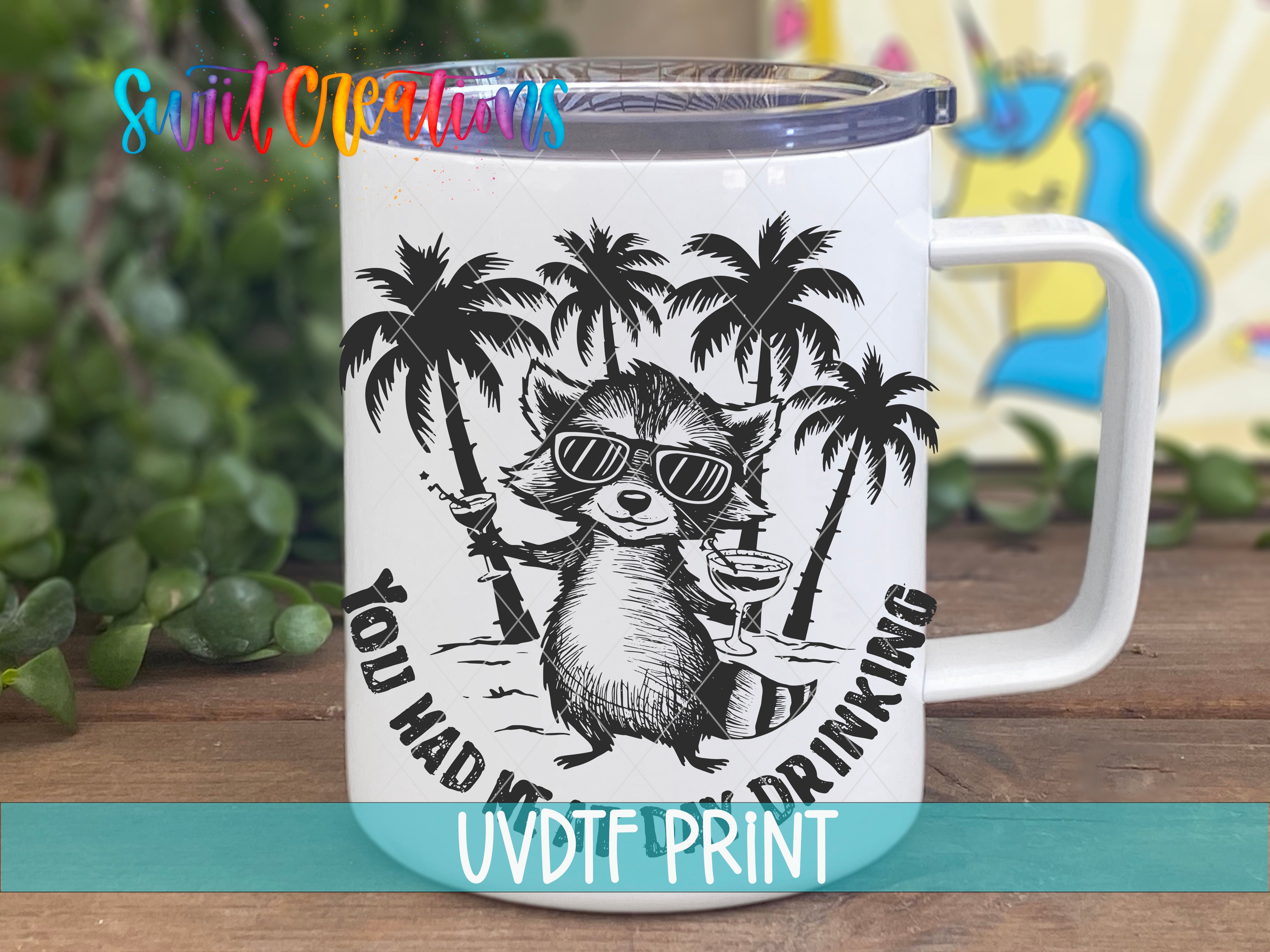 A white mug with a black and white illustration of a raccoon wearing sunglasses and holding a drink, surrounded by palm trees.