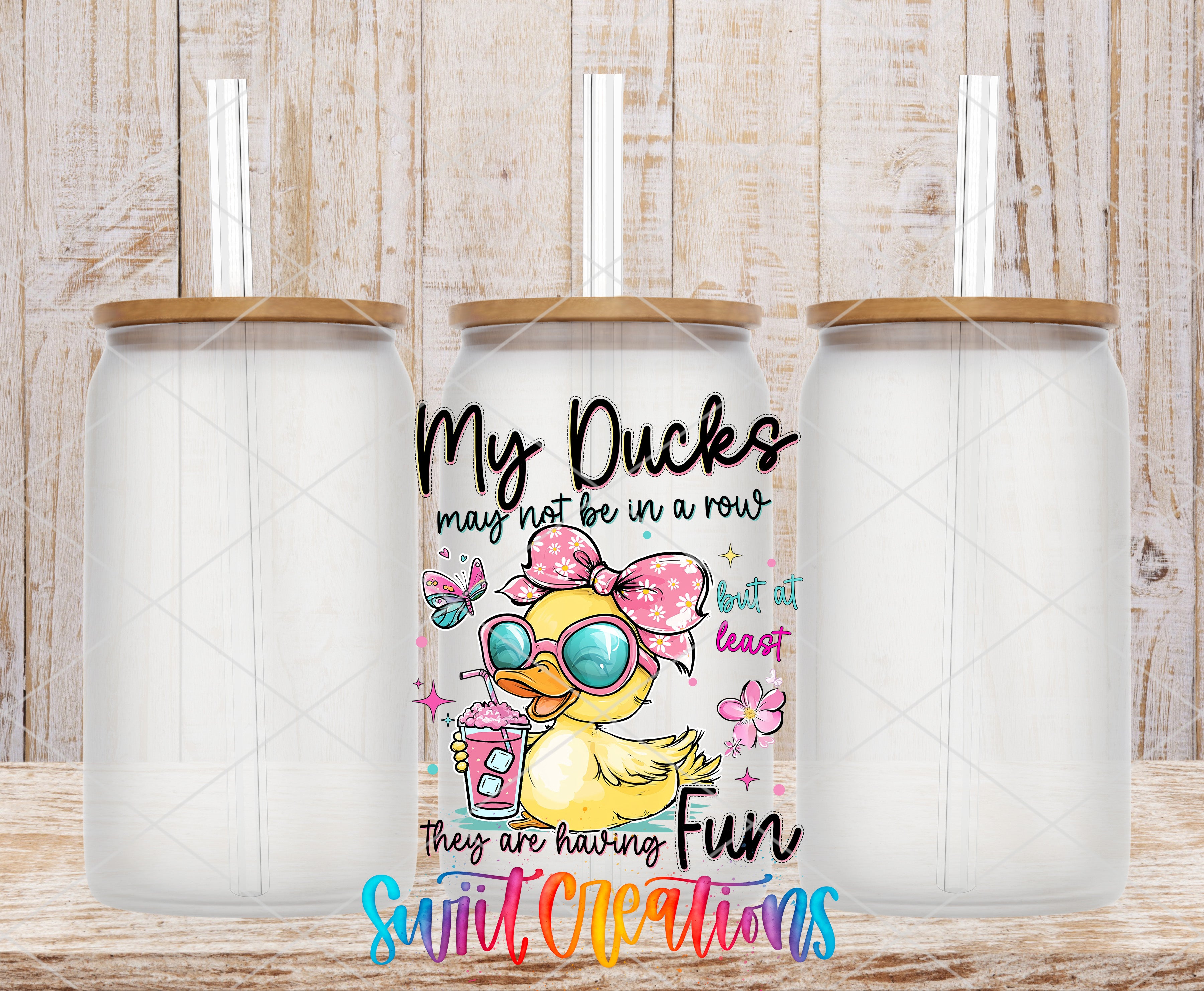 a colorful tumbler with a cartoon duck design and text, placed on a wooden surface.