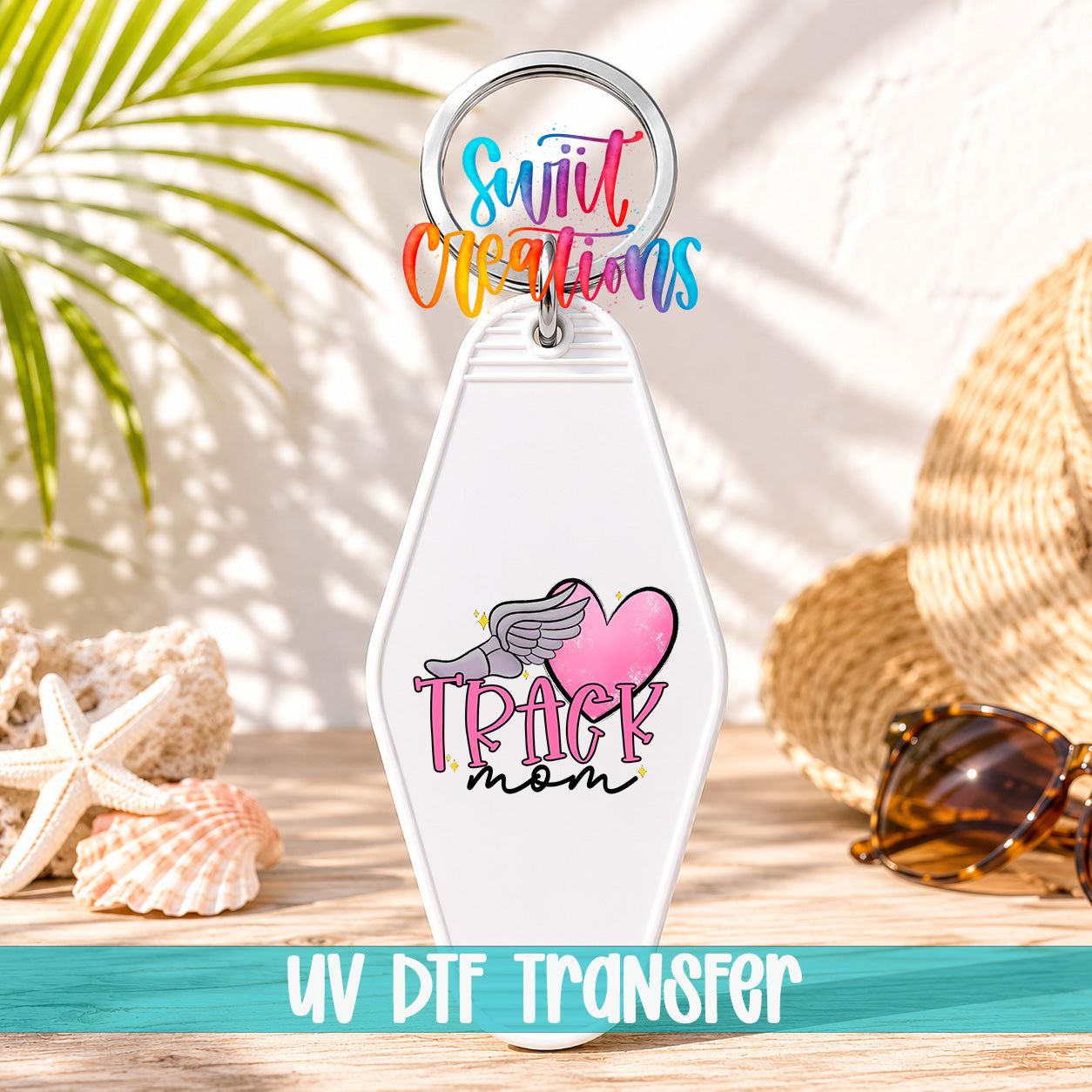 A keychain with a colorful design and text, placed on a wooden surface with sunglasses and a straw hat in the background.