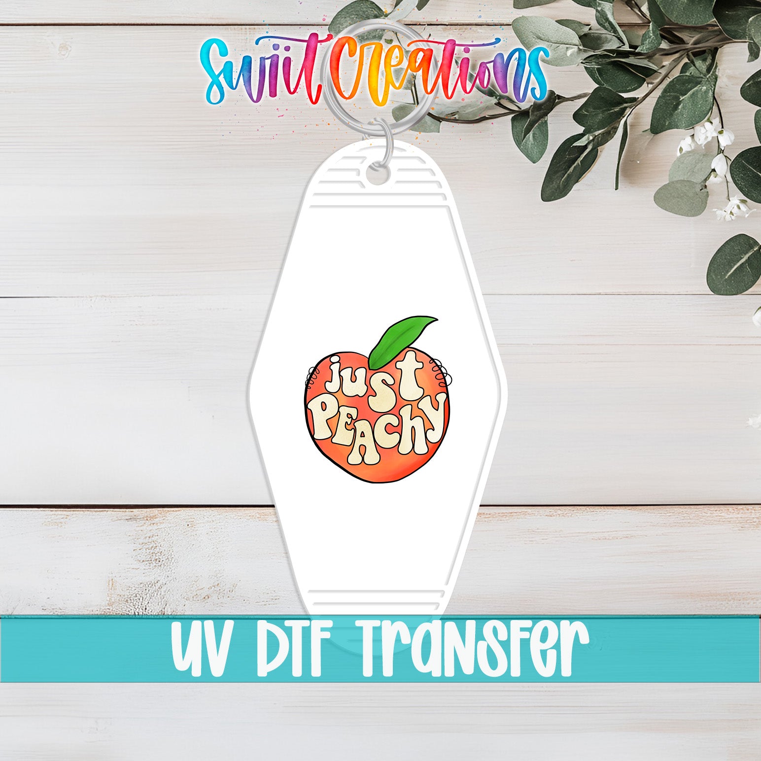 A keychain with a peach design and the text "Just Peachy" printed on it, placed on a wooden surface with some greenery in the background.
