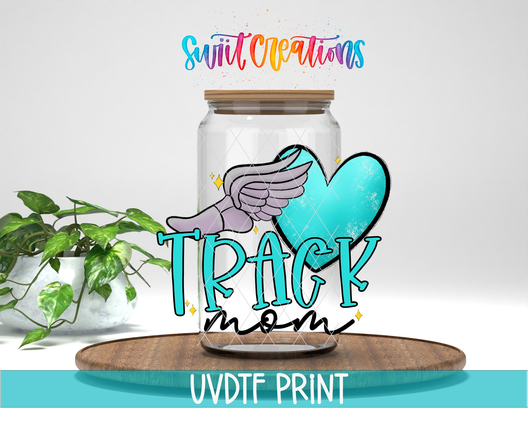 a glass jar with a winged design and the text "TRACK mom" written on it, placed on a wooden surface.