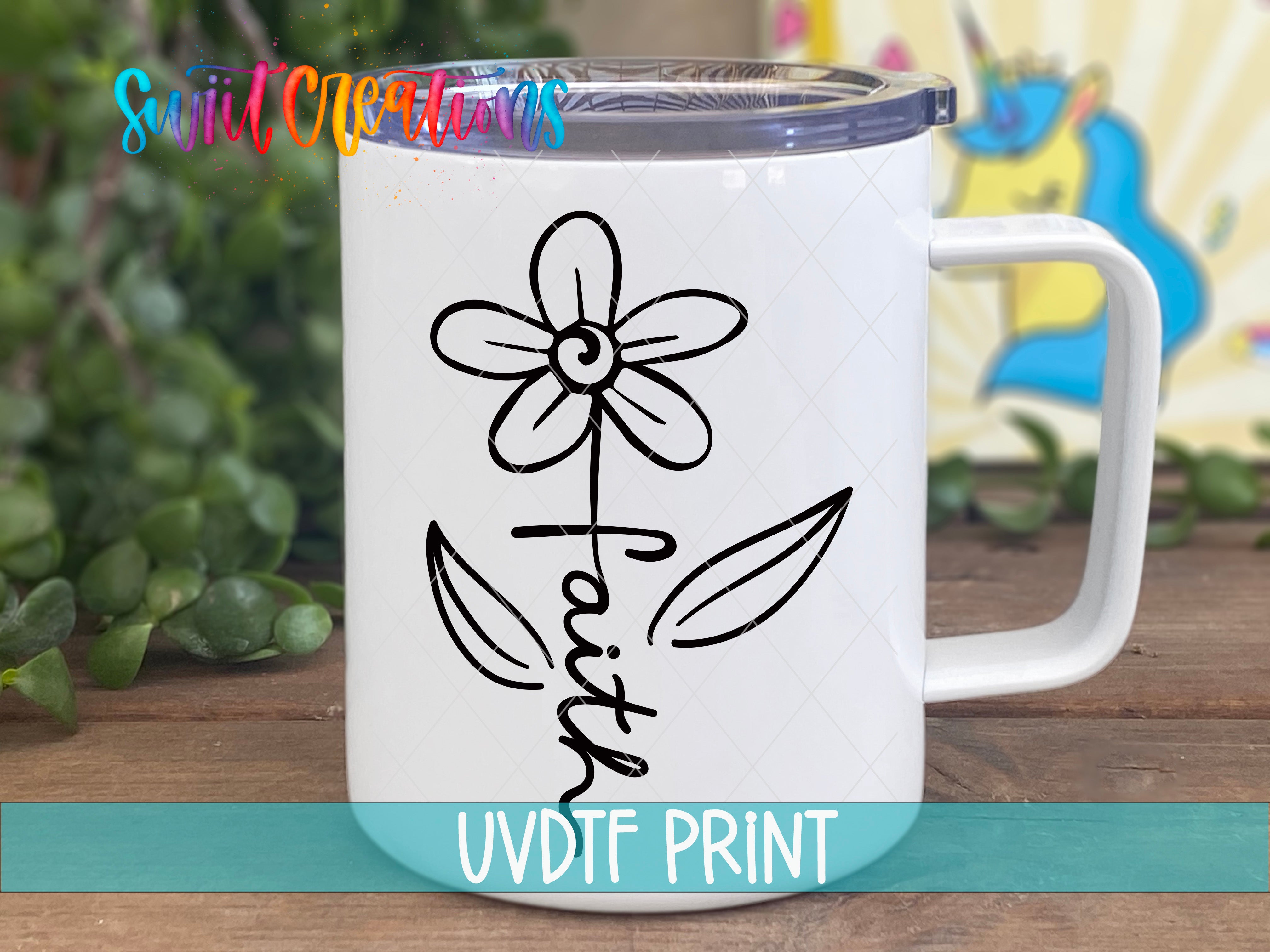 A white ceramic mug with a black flower design and the word "Faith" printed on it, placed on a wooden surface.