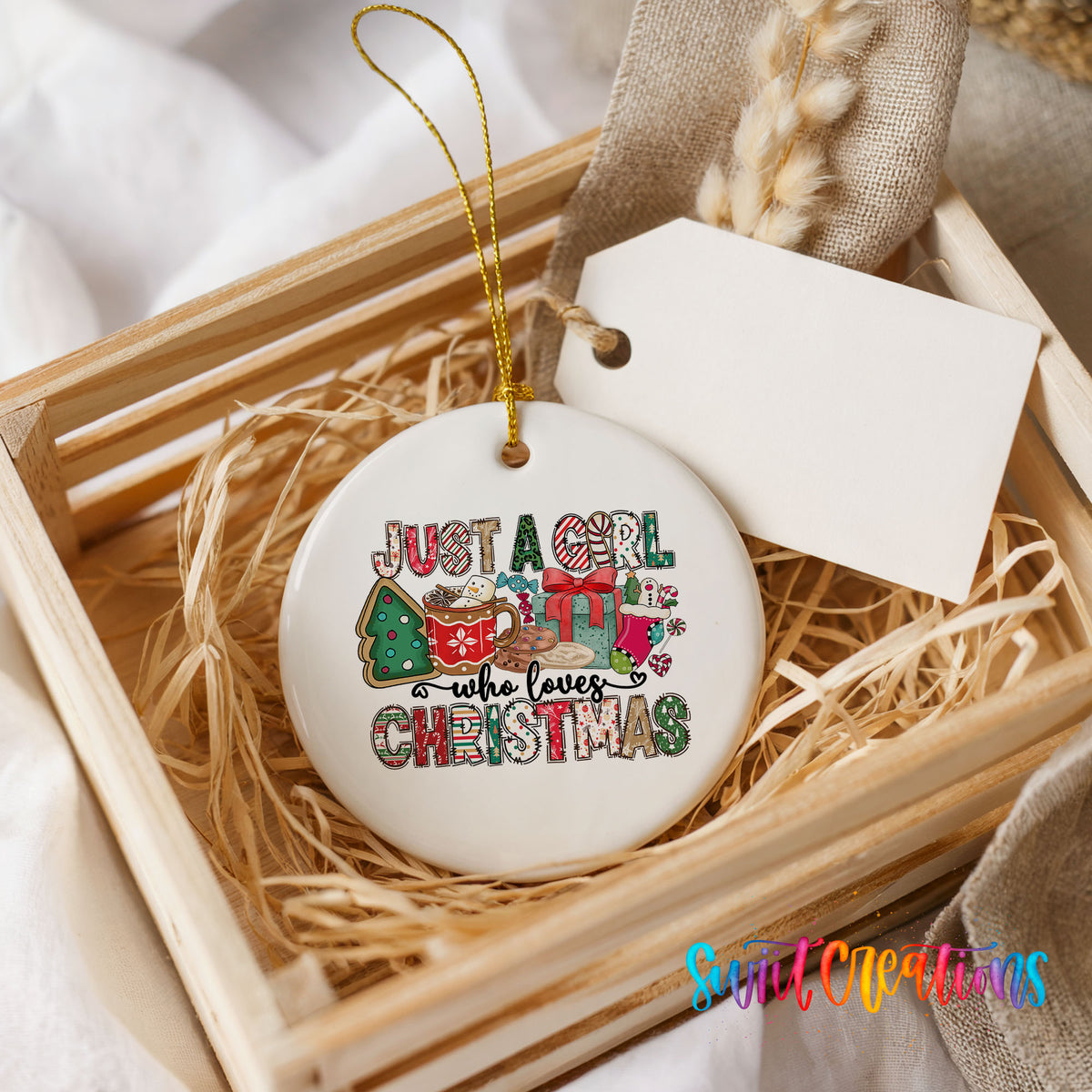 A white ceramic ornament with a colorful design, placed in a wooden crate filled with straw.