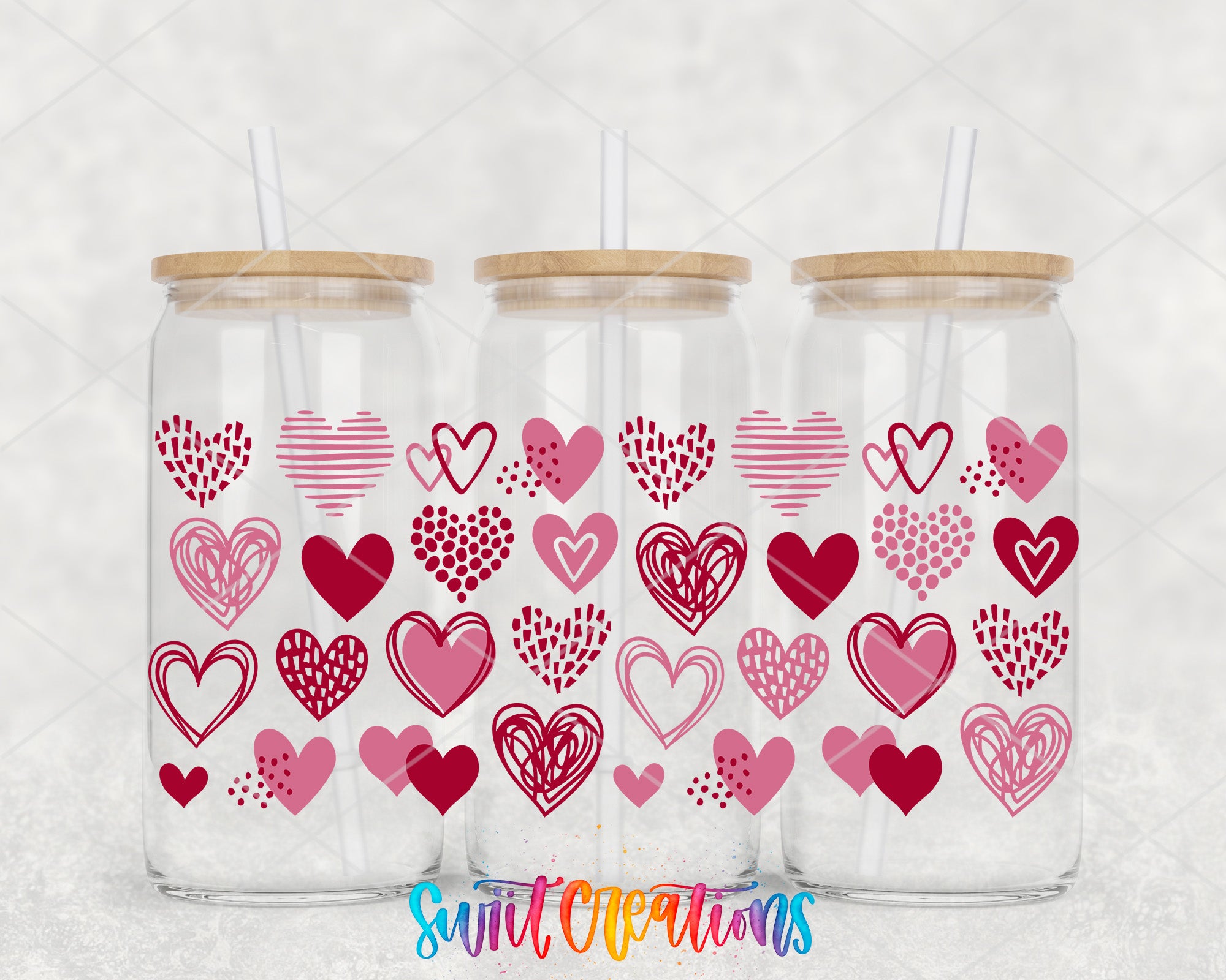 Three glass jars with wooden lids, each containing a straw. The jars are decorated with pink hearts and other heart-related designs.
