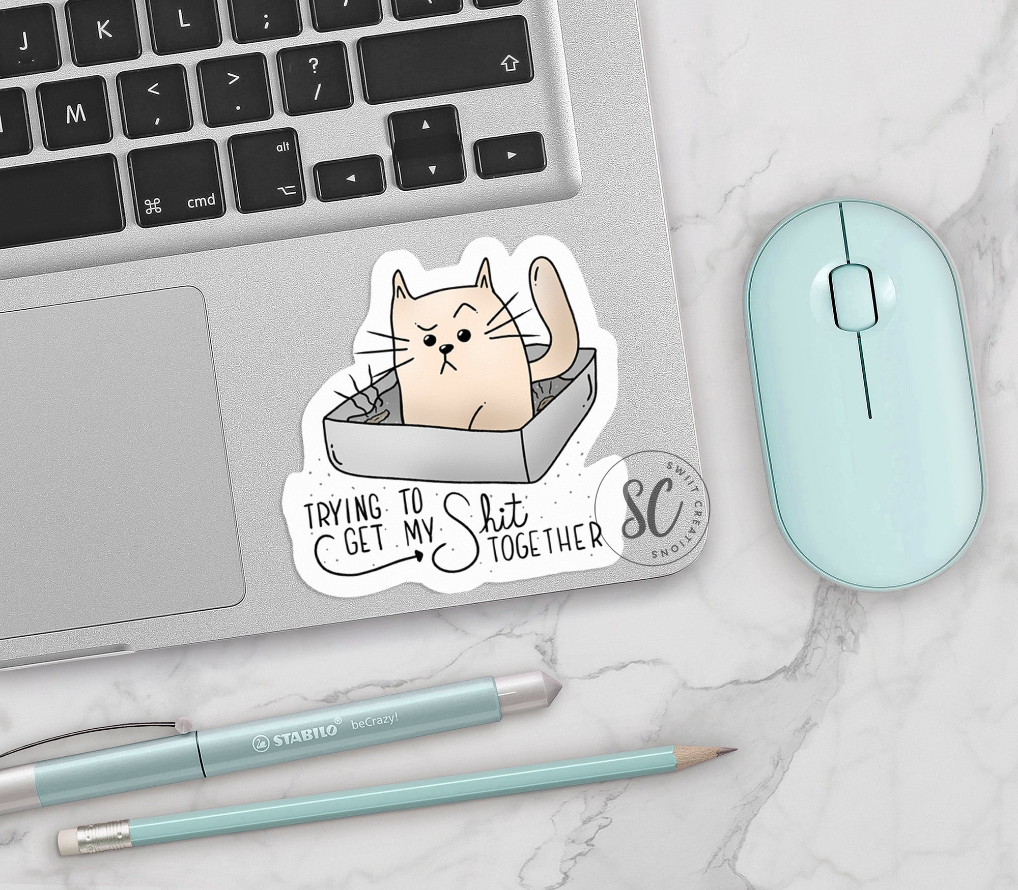 a sticker of a cat in a box on a laptop