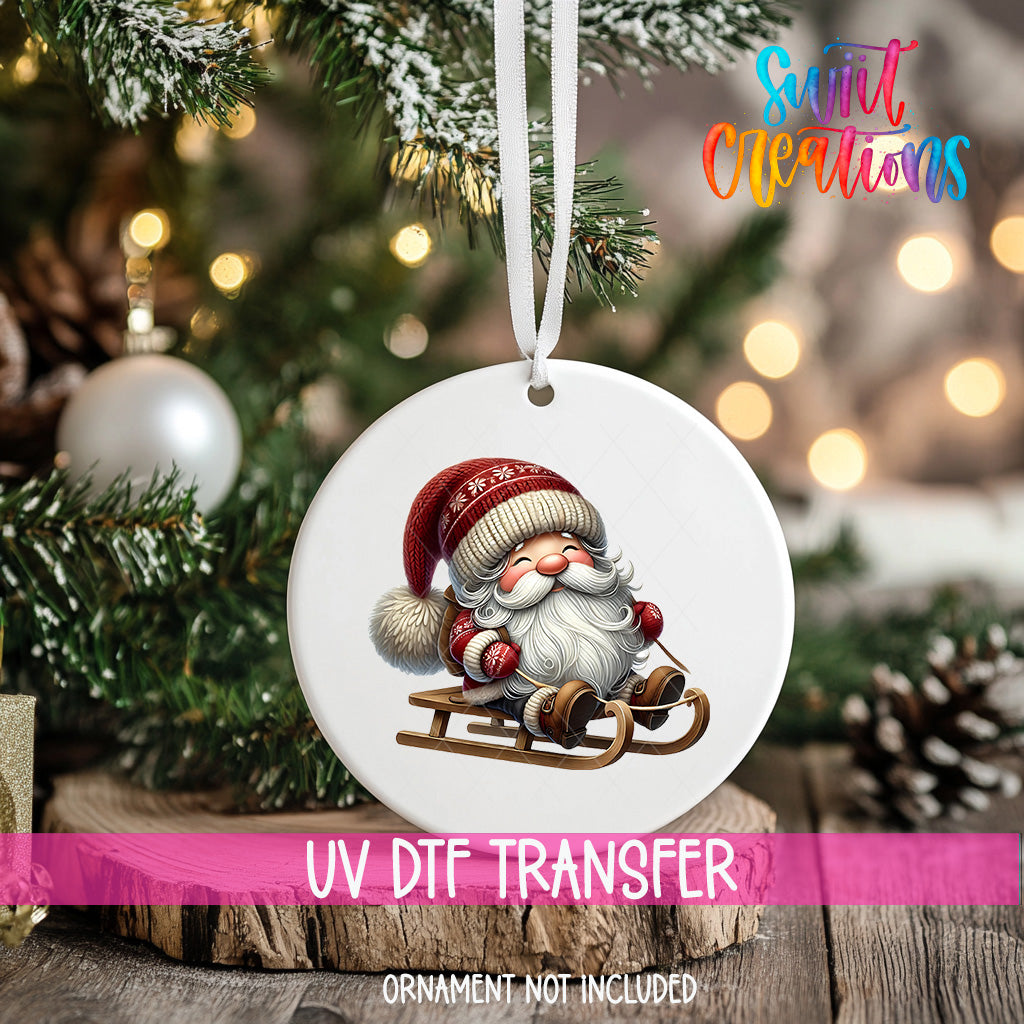 A white ornament with a Santa Claus image is hanging on a Christmas tree, with a blurred background of pine branches and twinkling lights.