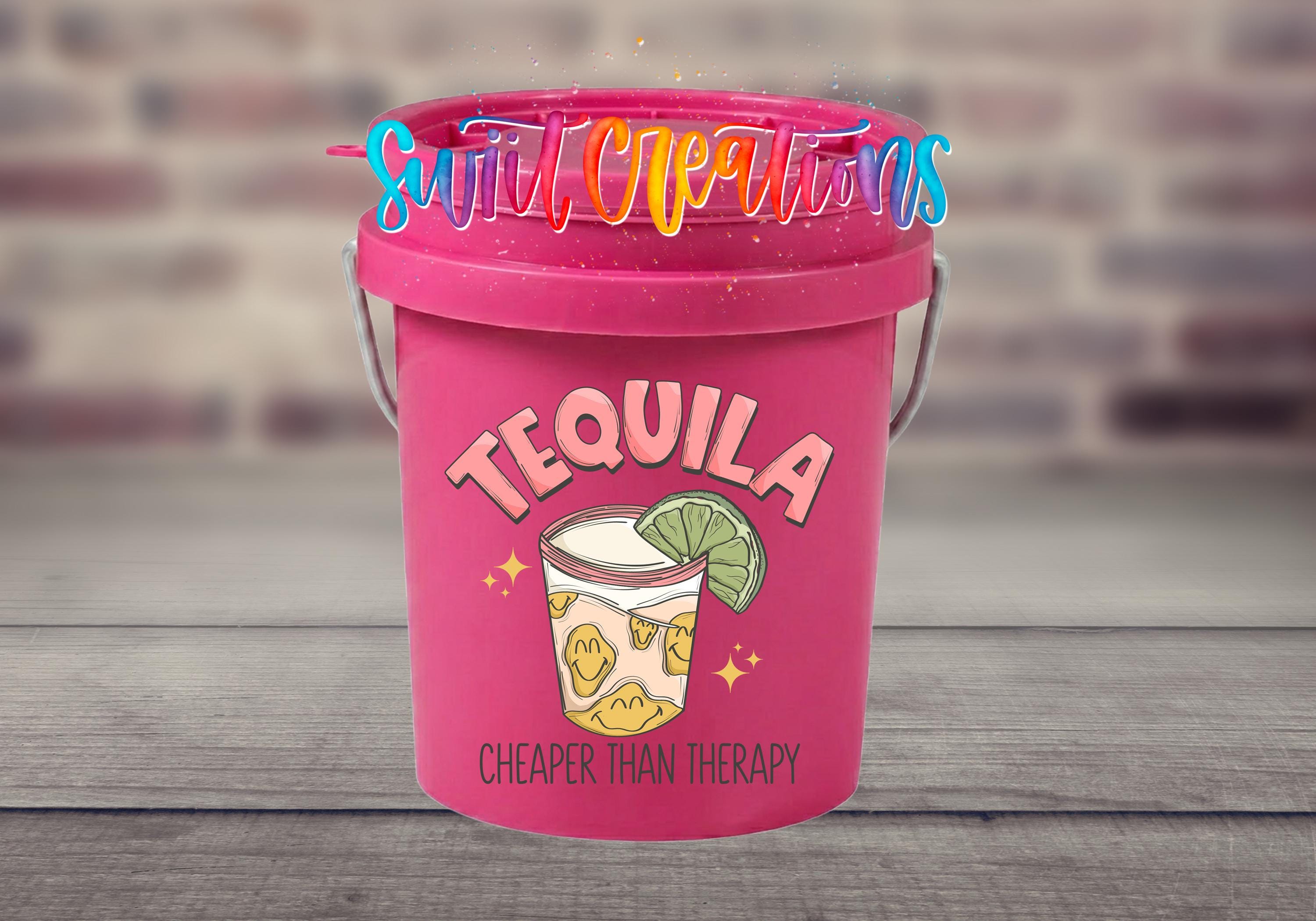 A pink bucket with a tequila-themed design and the text "Cheaper than therapy" on it.