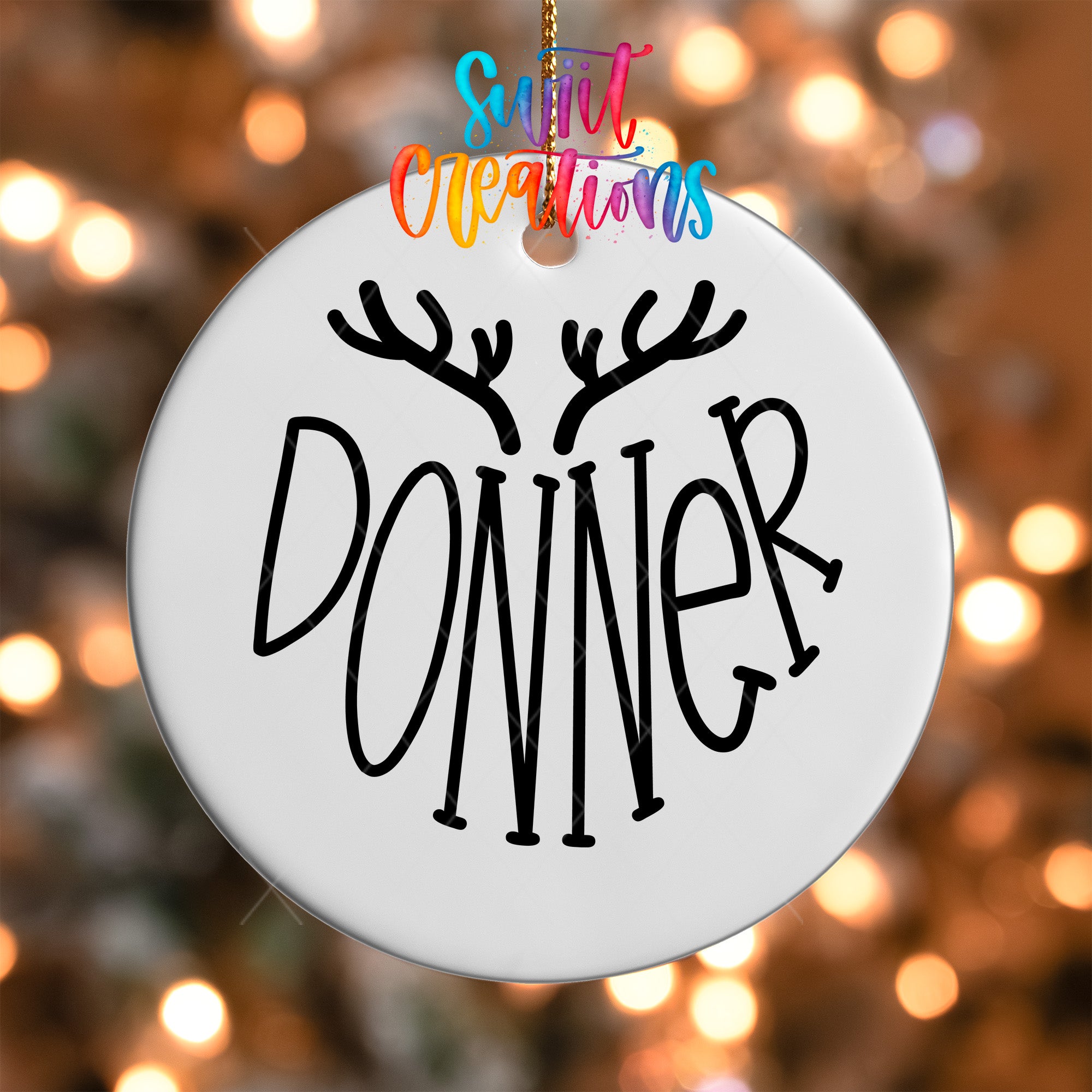 A white ornament with the word "DONNER" written on it, hanging against a background of colorful lights.