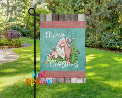A garden flag with a gnome and a Christmas tree design, along with the text "Merry Christmas" displayed on it.